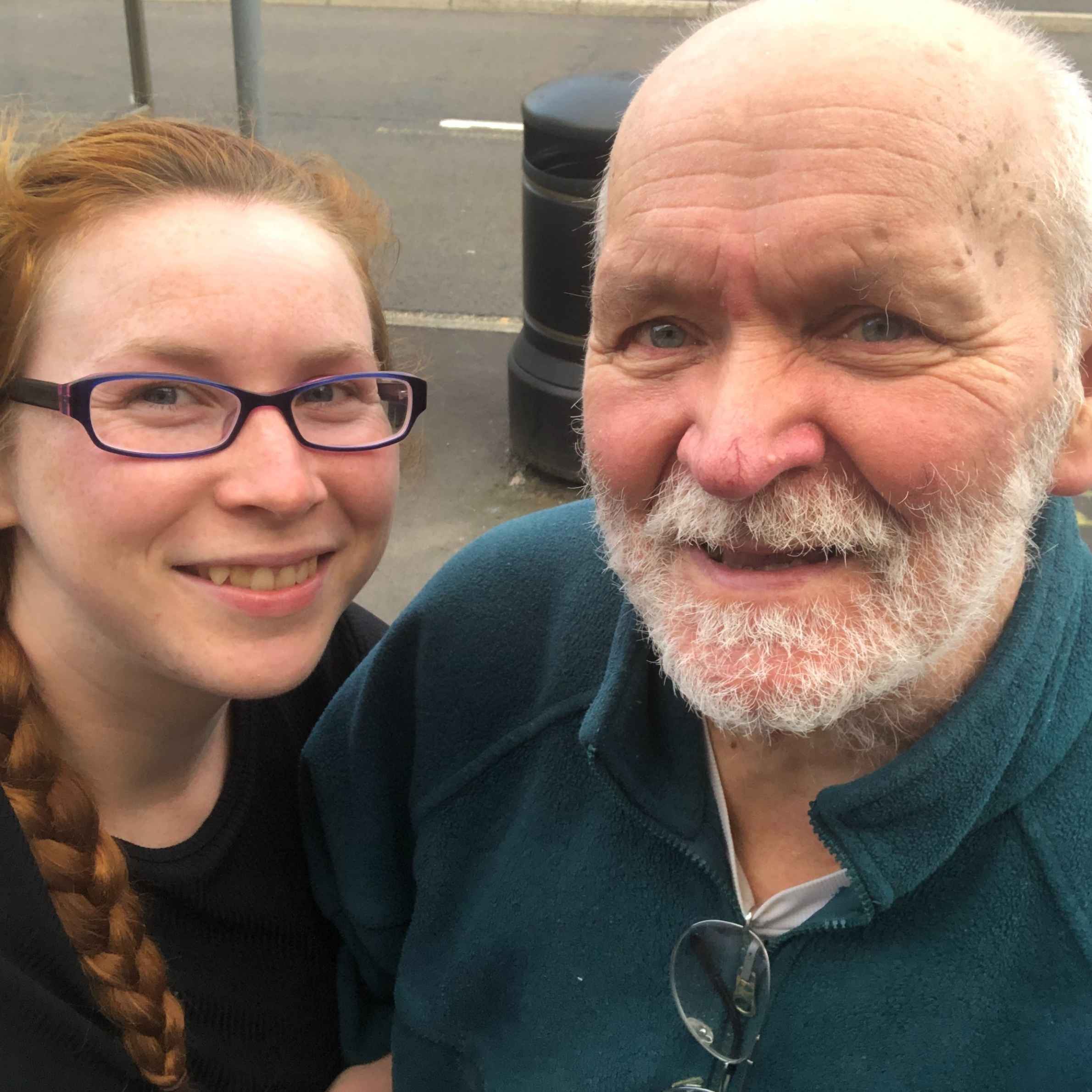 A lady and an older man are in the photo. The lady has ginger hair in a plait and is wearing glasses. The man has grey hair and a beard and he is wearing a teal zip up fleece.