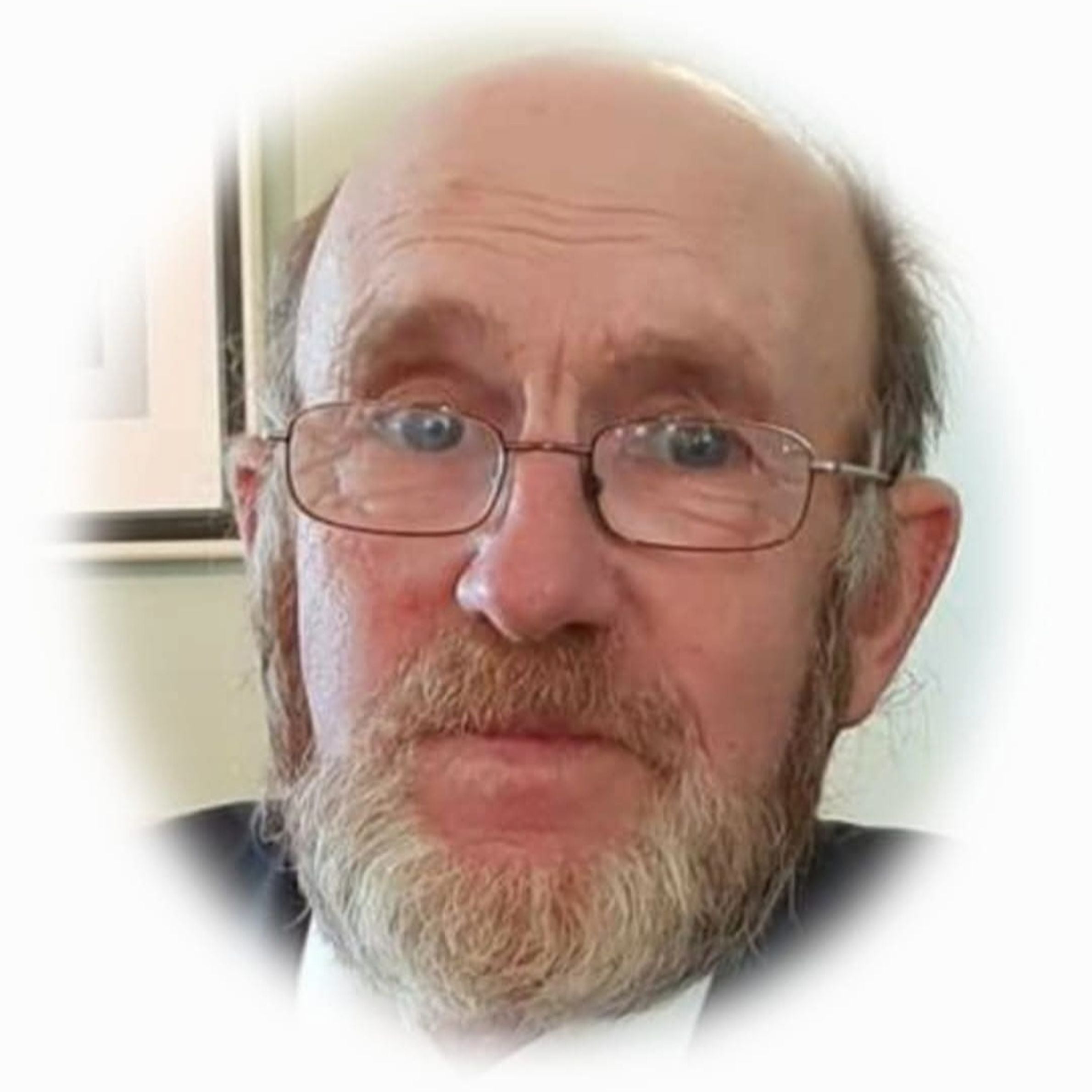 older man wearing glasses with grey hair and grey beard and blue eyes. the photo has a white boarder