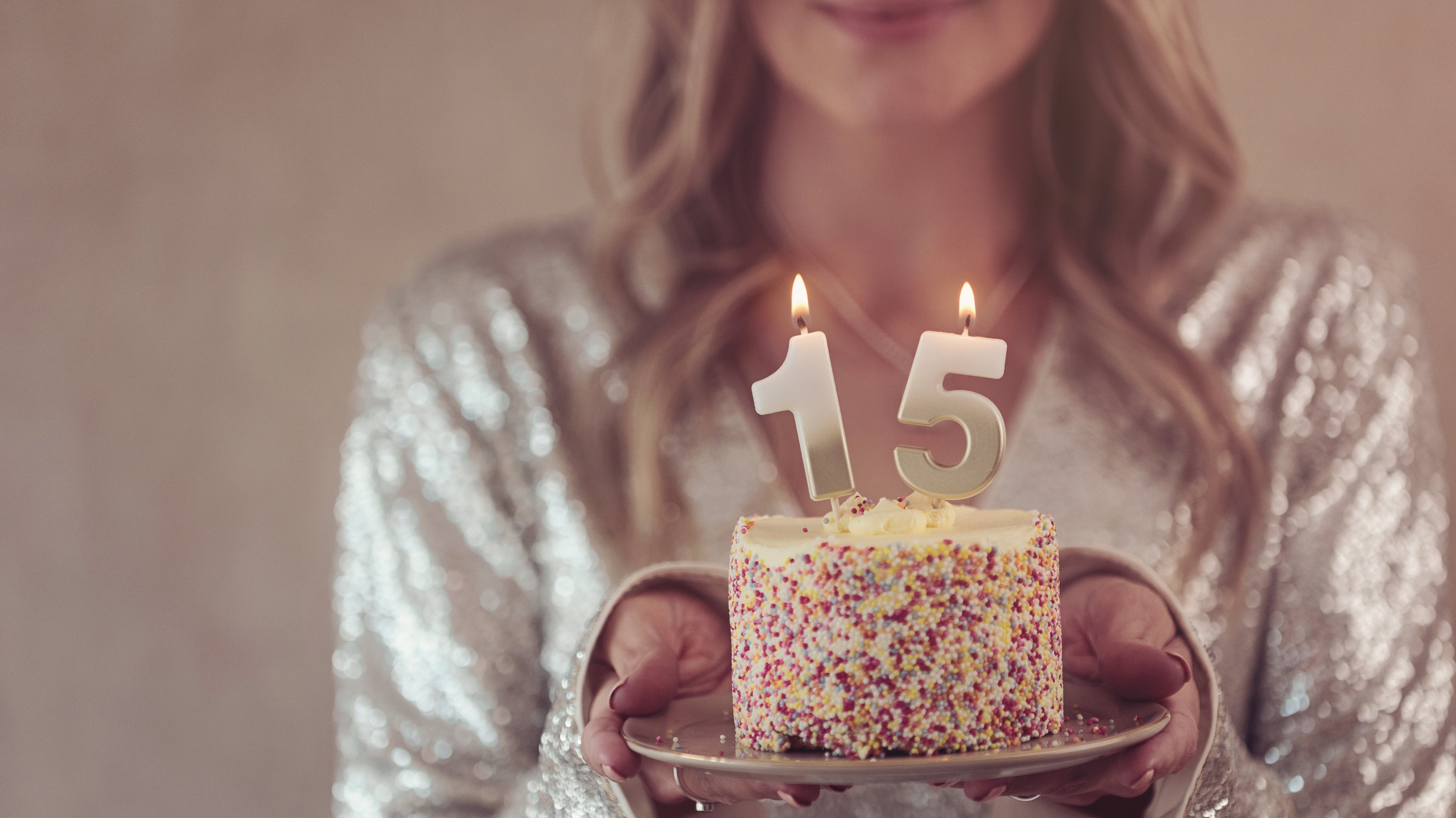 A woman holding a birthday cake with 15 candles