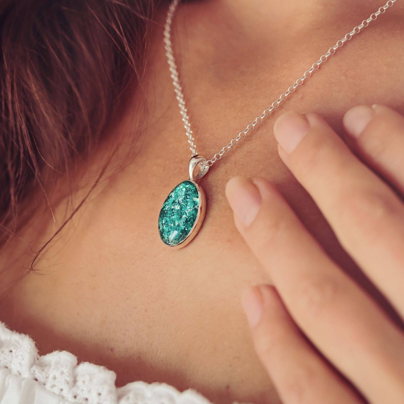 A woman wearing a Cremation Ashes Oval Necklace in green