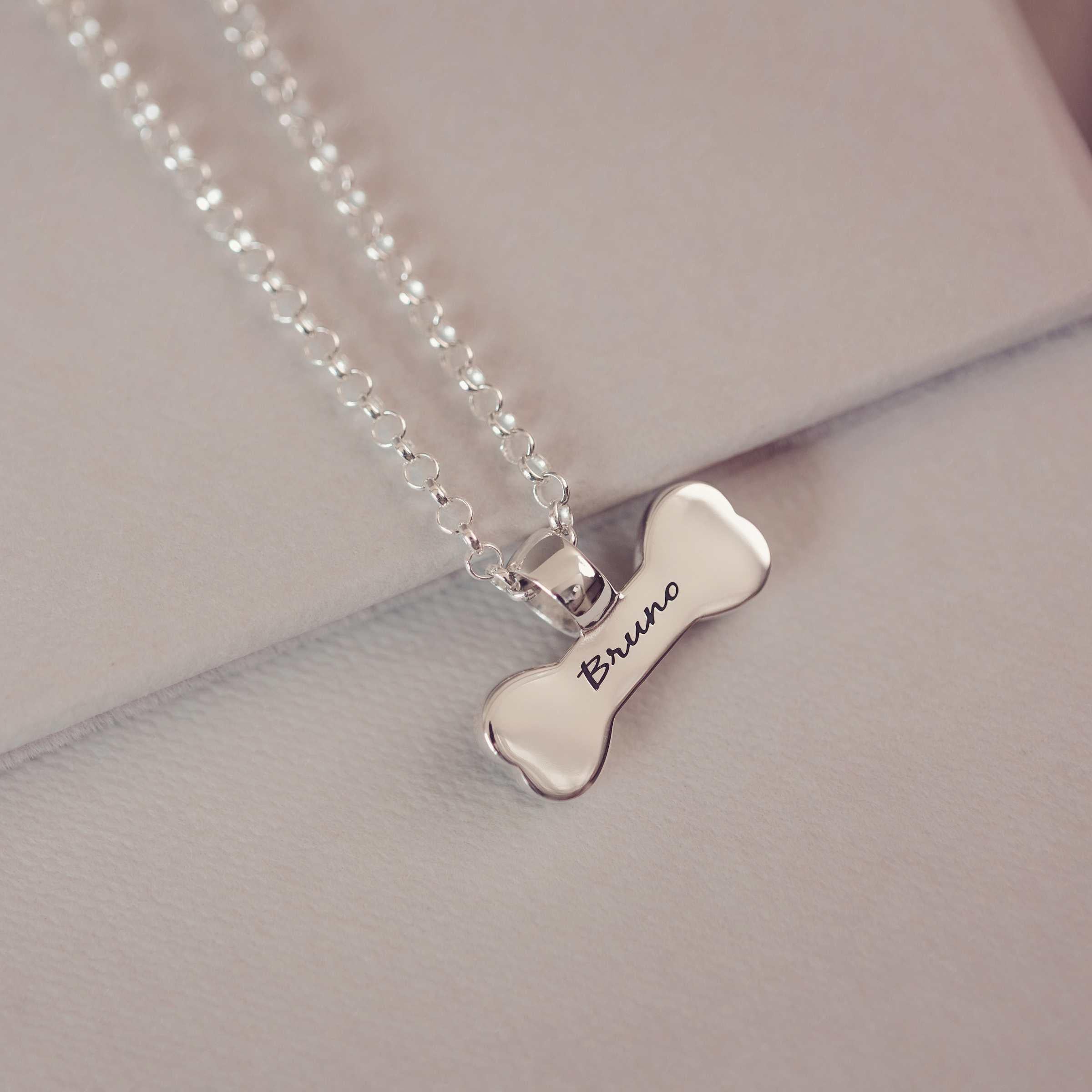Silver bone-shaped pendant necklace with 'Bruno' engraving on a light gray background
