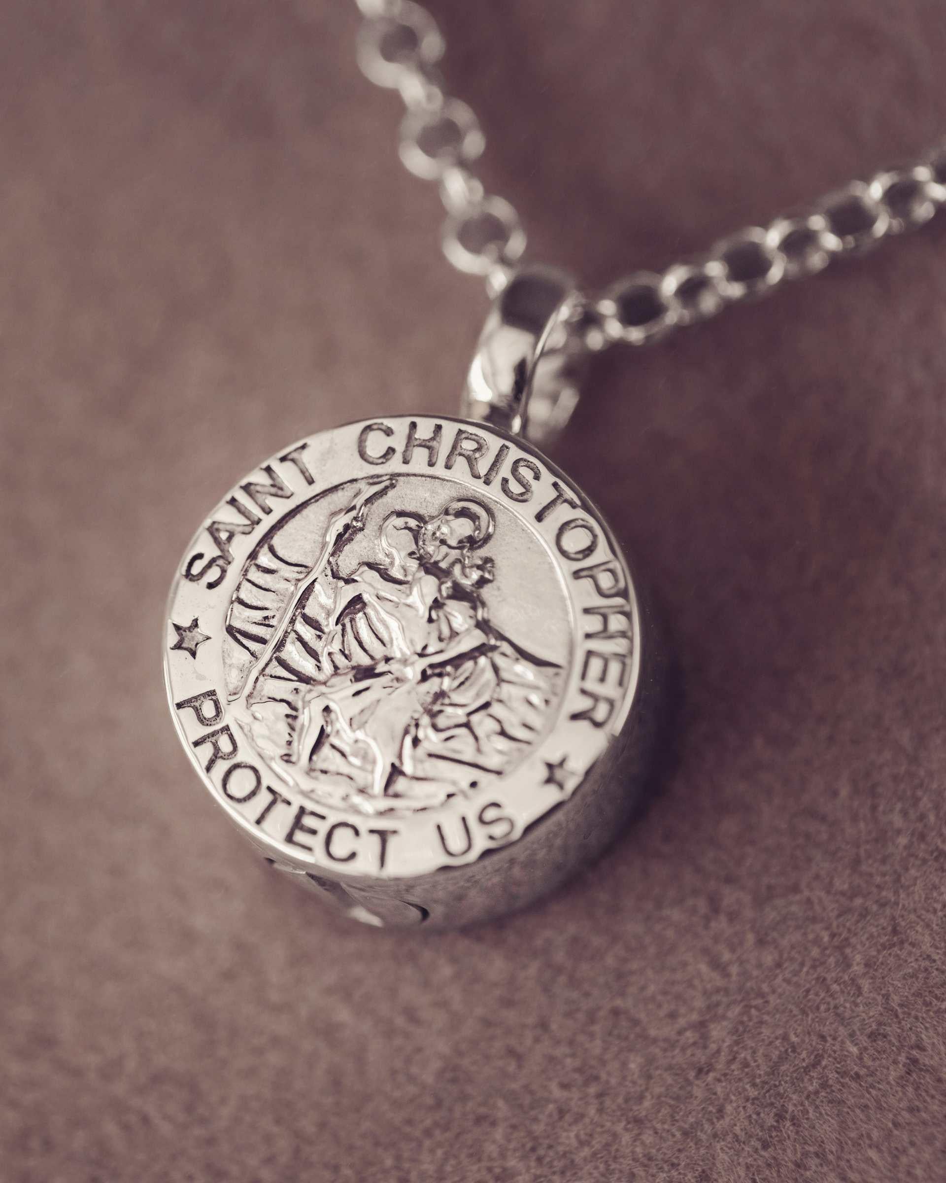 Silver Saint Christopher pendant on a chain against a brown background