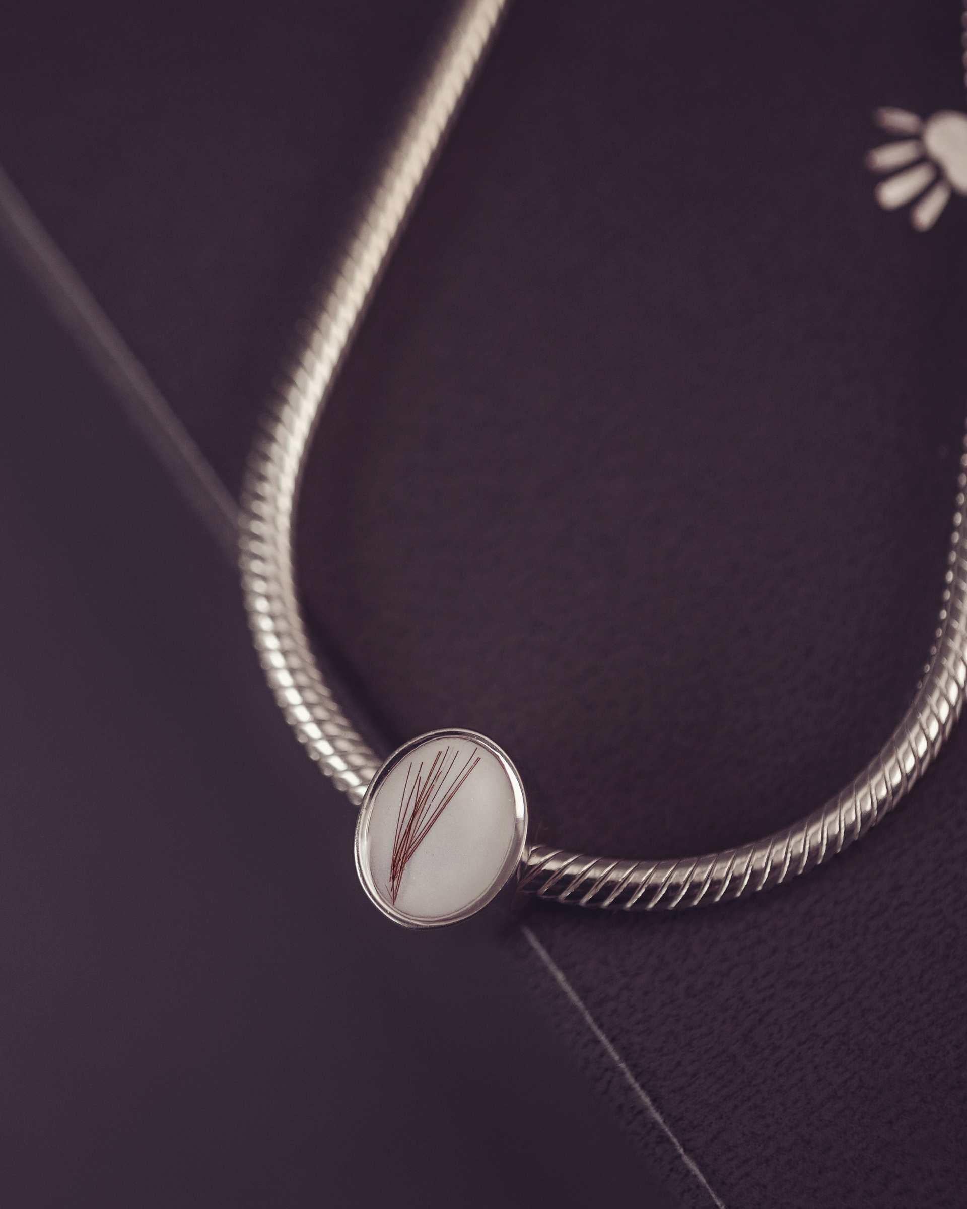 Silver thick snake chain with an oval charm on a dark background