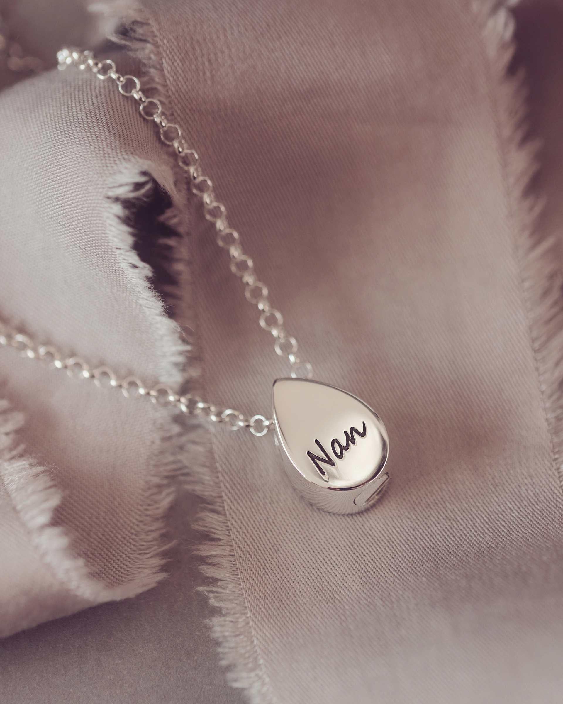 Silver necklace with a teardrop-shaped pendant engraved Nan on a soft fabric background