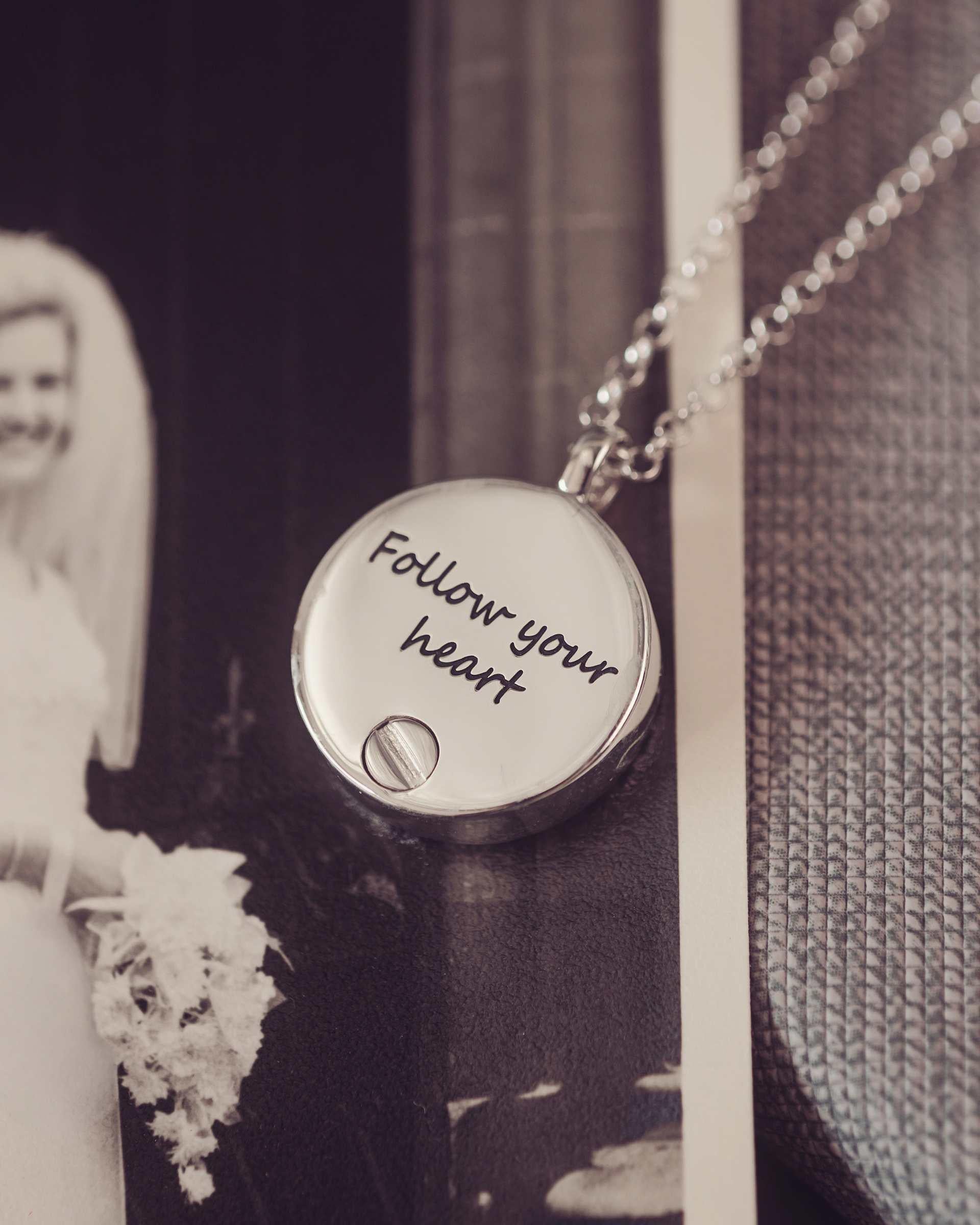 Necklace with 'Follow your heart' pendant in front of a black and white photo of a bride.