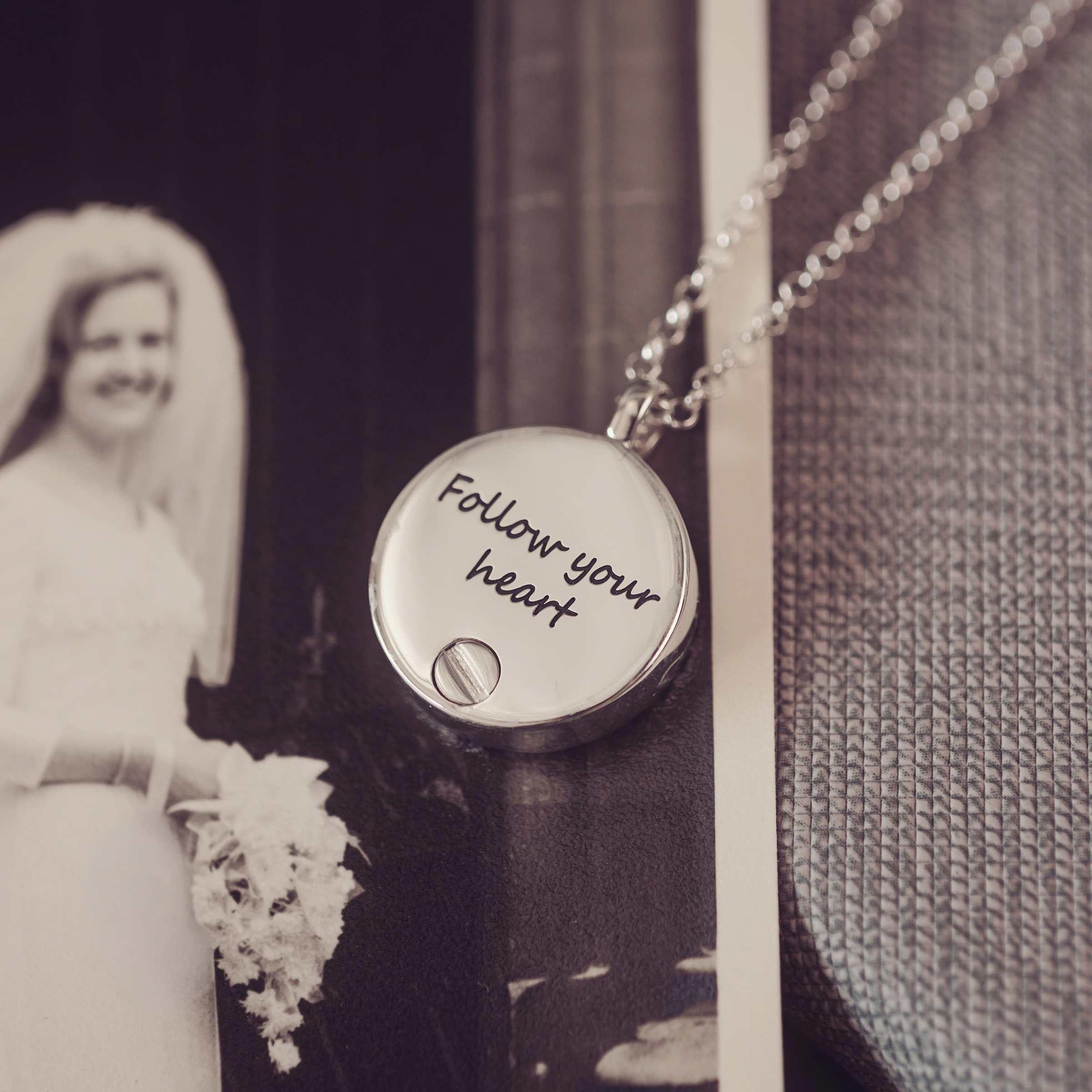 Necklace with 'Follow your heart' pendant in front of a black and white photo of a bride.