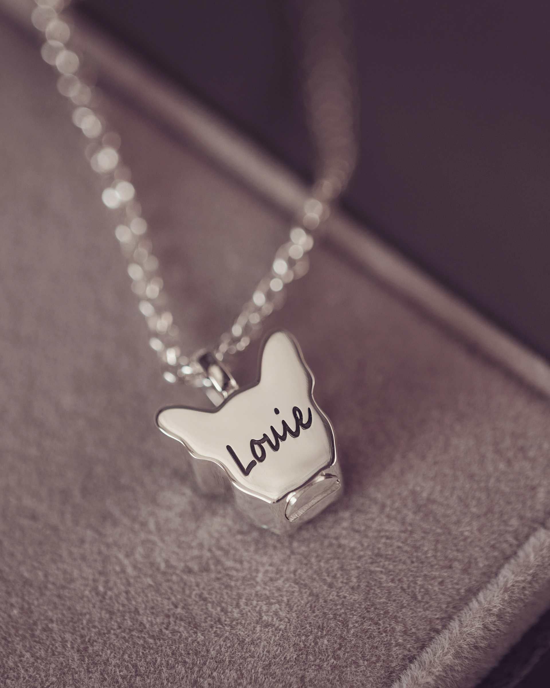 Silver necklace with Louie engraved on a textured surface