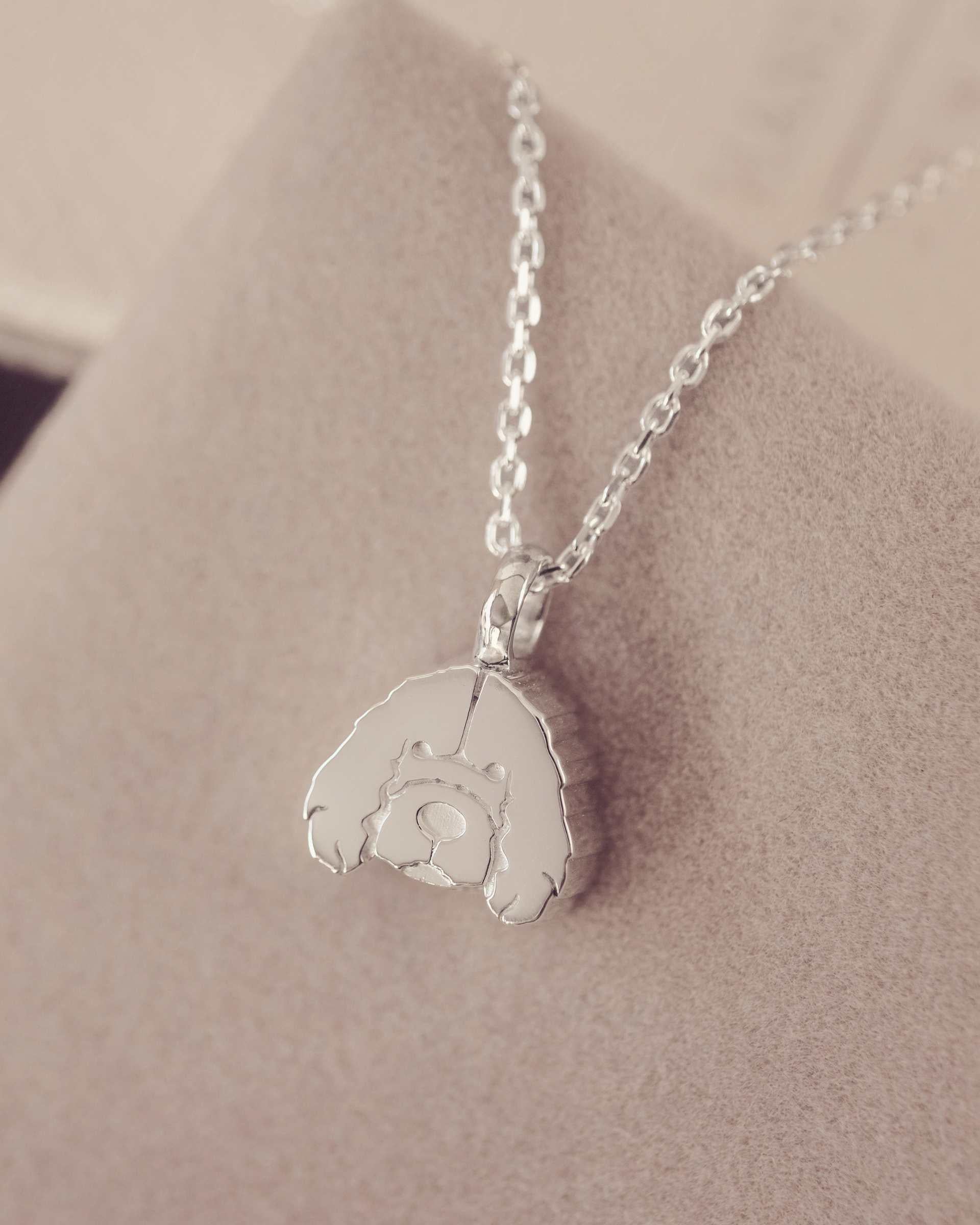 Silver necklace with a cockerpoo pendant on a soft beige background