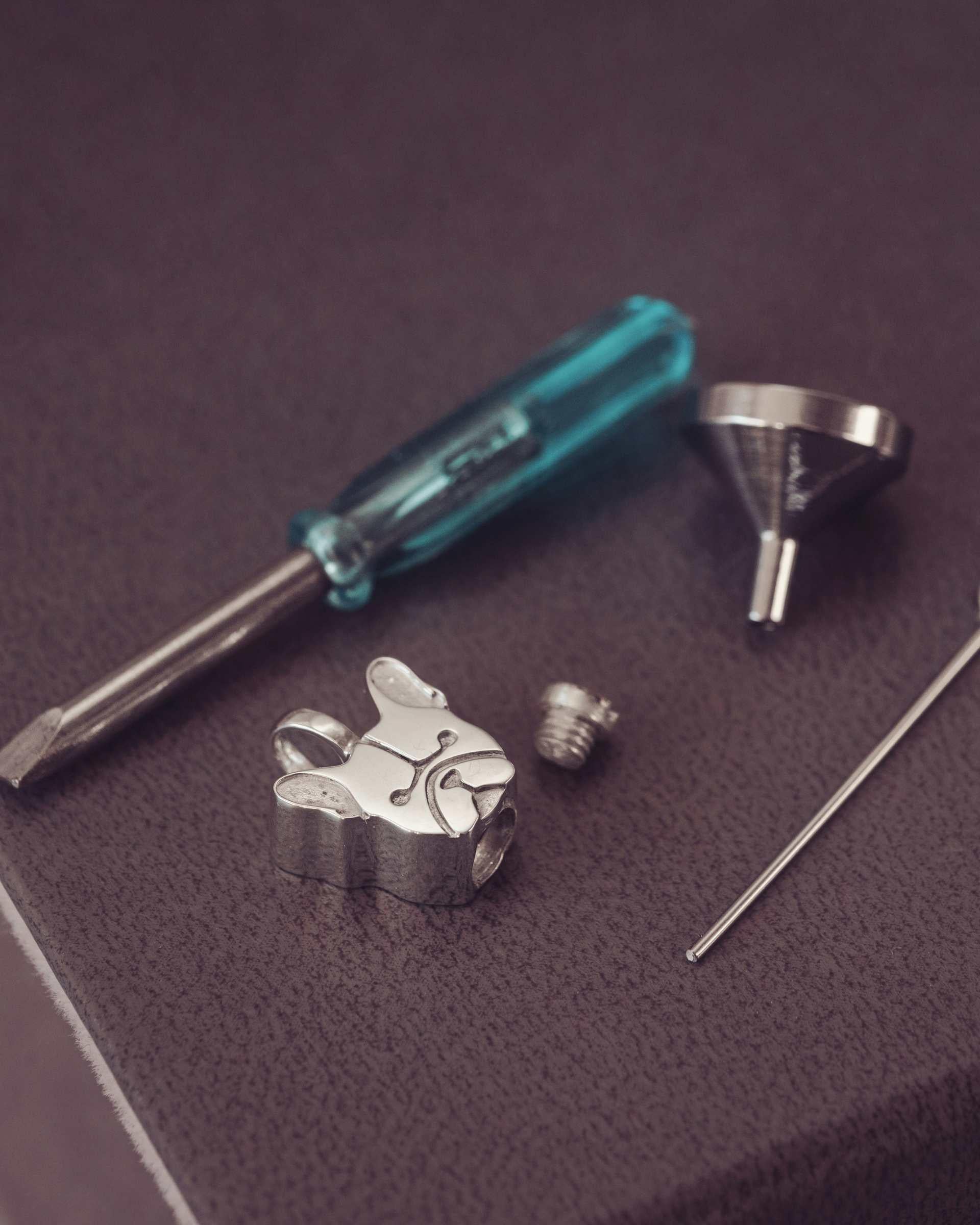 silver jewellery components and tools on a dark background