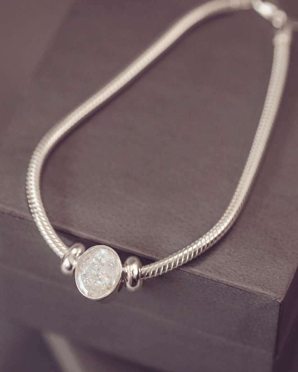 Silver bracelet with a round, textured bead on a dark surface