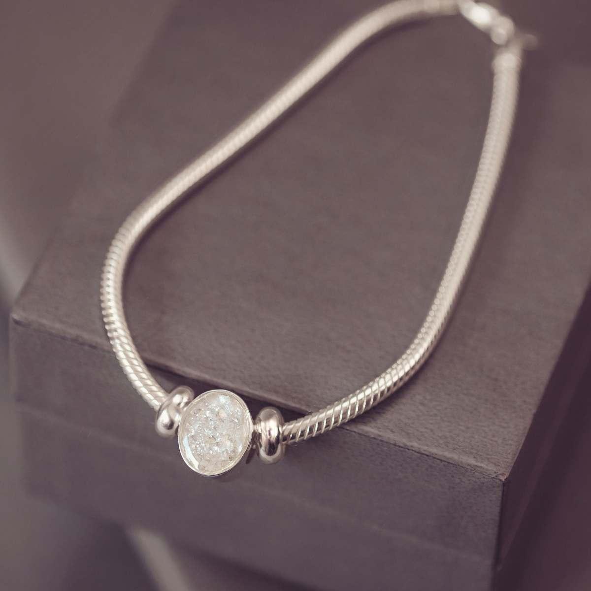 Silver bracelet with a round, textured bead on a dark surface