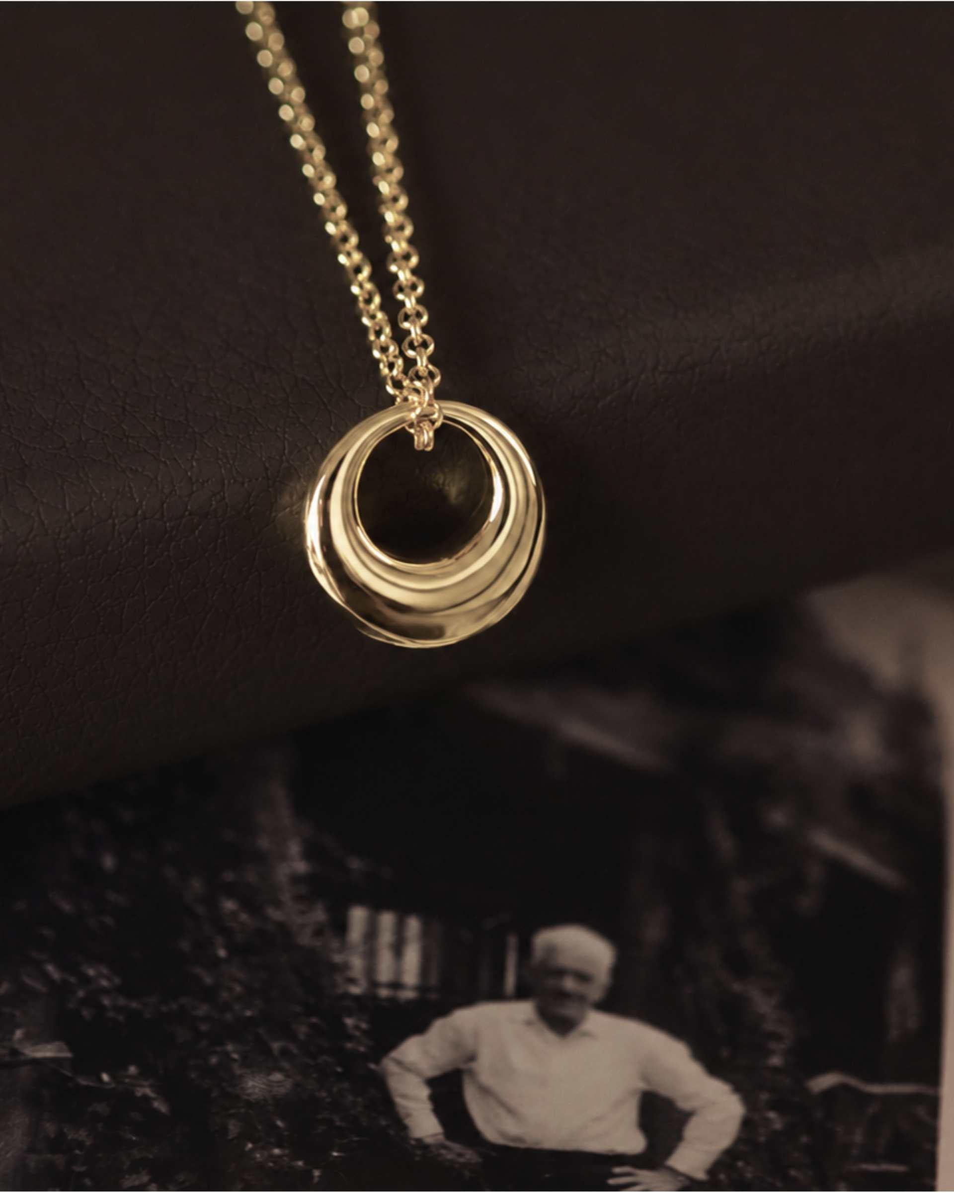 Gold necklace with a black pendant on a dark background