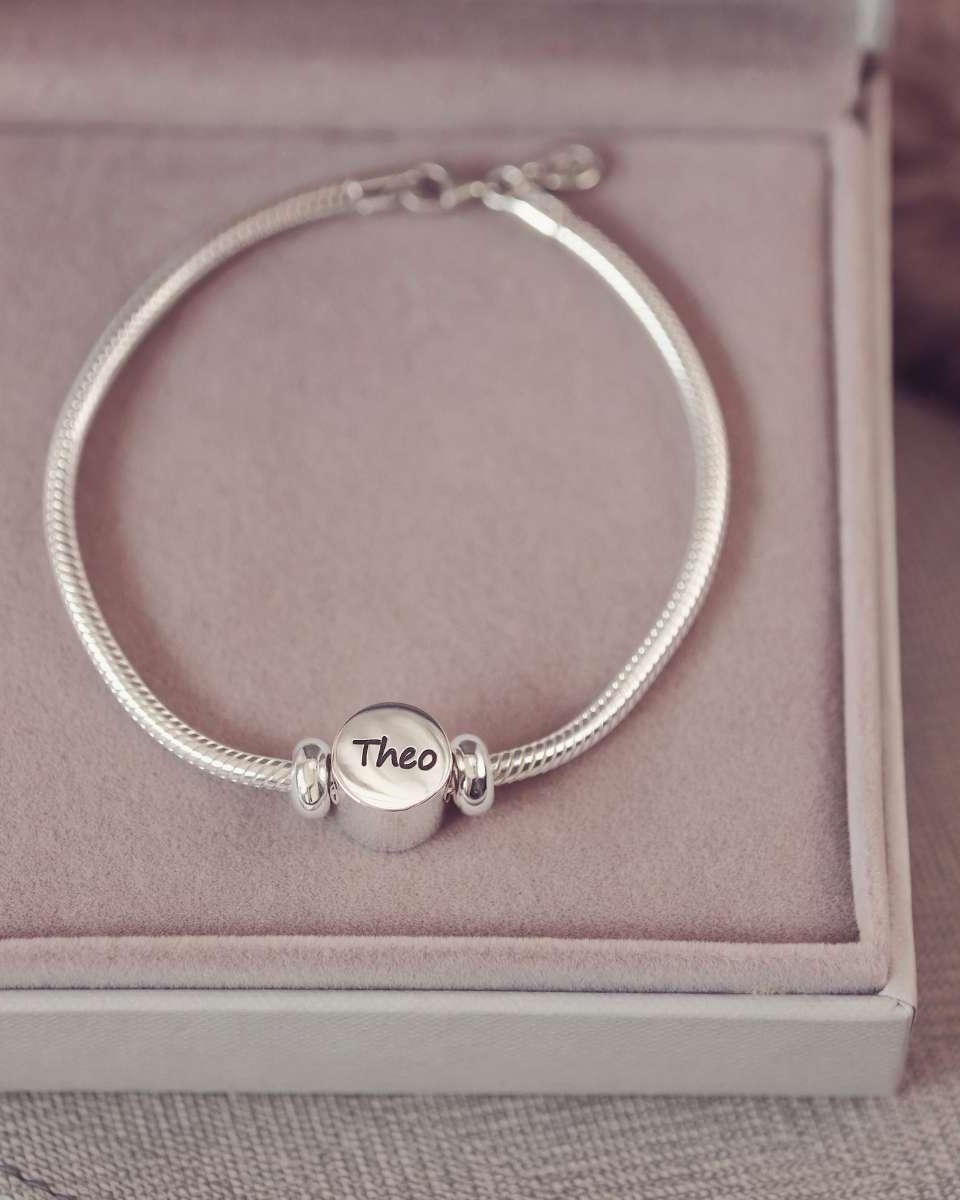 Silver bracelet with a 'Theo' charm on a pink cushioned box