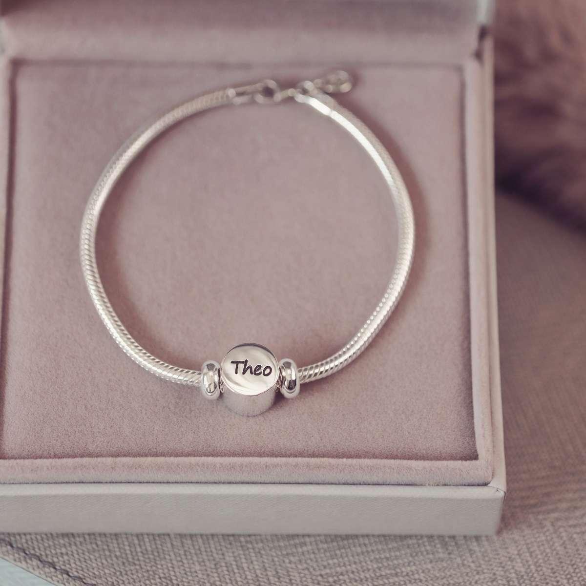 Silver bracelet with a 'Theo' charm on a pink cushioned box