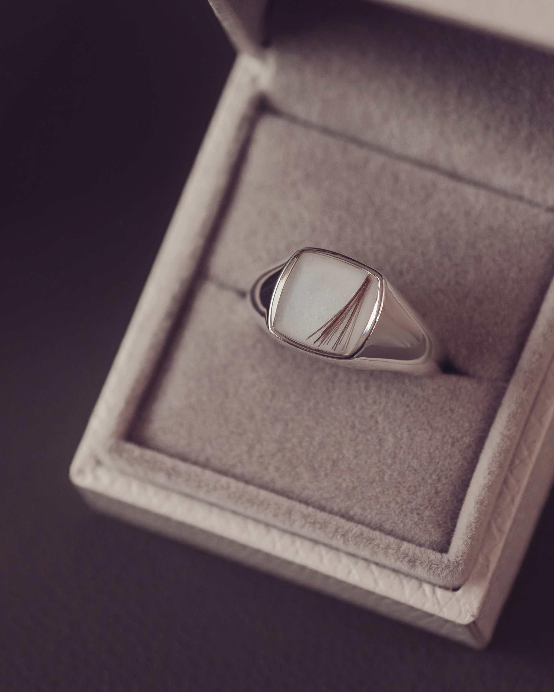 Silver ring with hair and resin in a jewelry box on a dark background