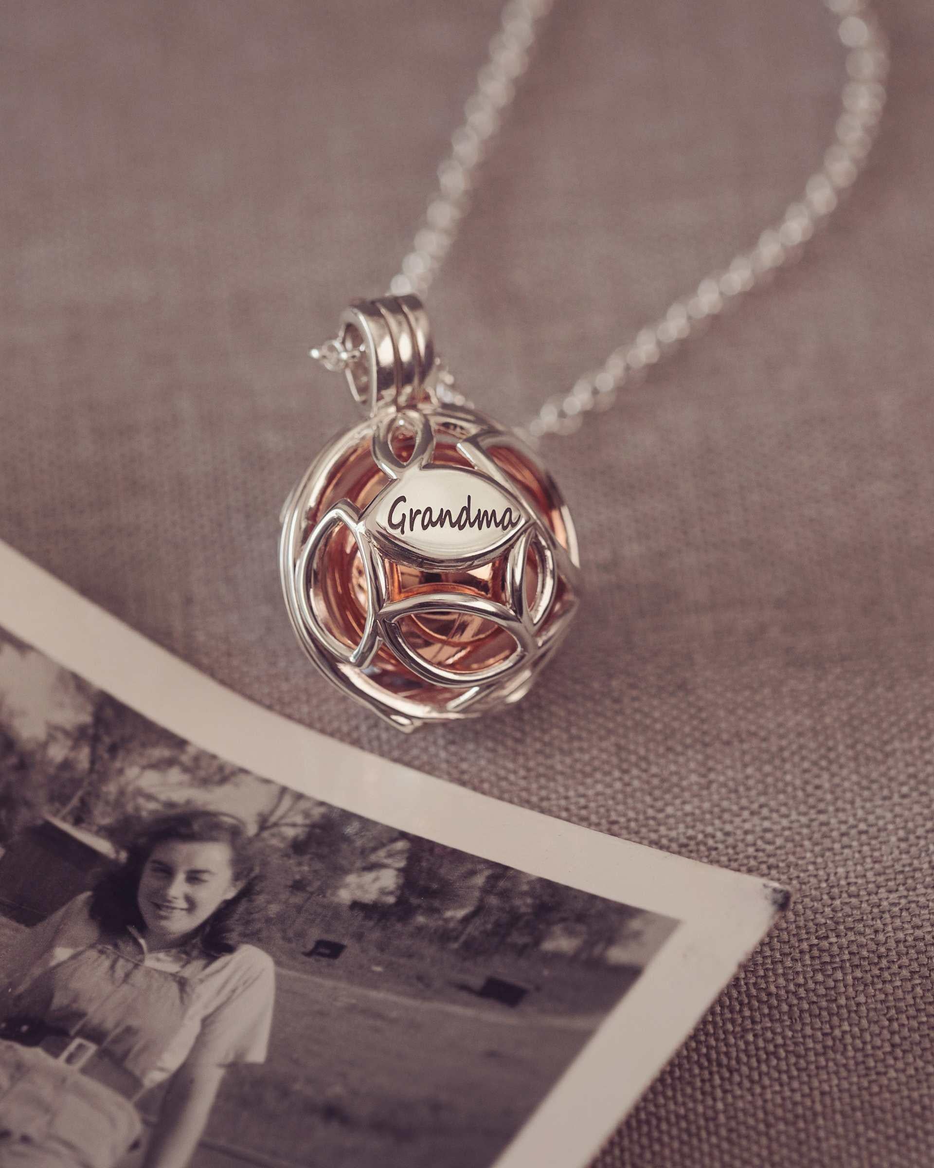 Necklace with a 'Grandma' pendant on a textured surface with an old photo underneath.