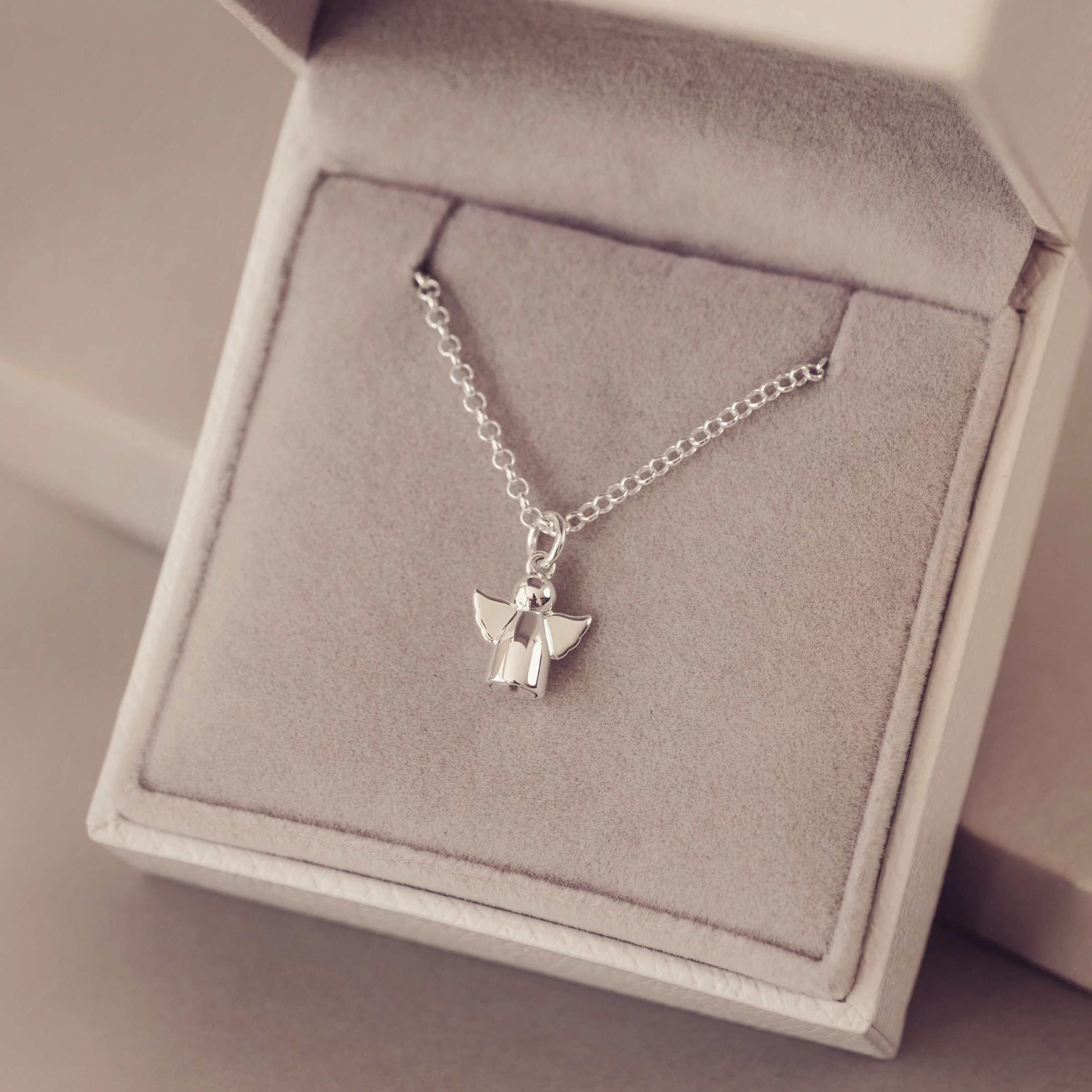 Silver angel pendant necklace on a soft gray jewellery box