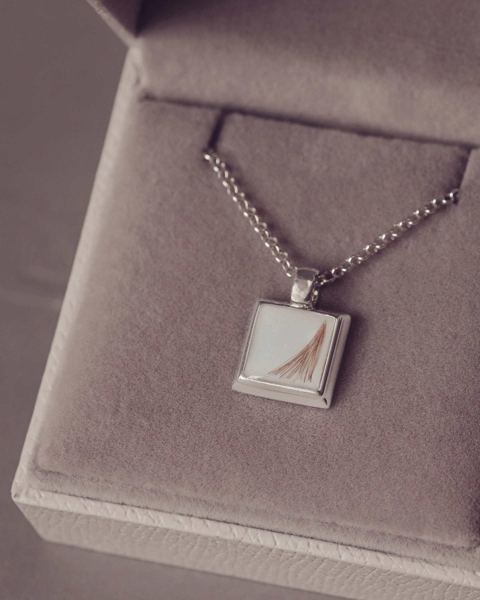 Silver necklace with a square pendant on a gray textured surface