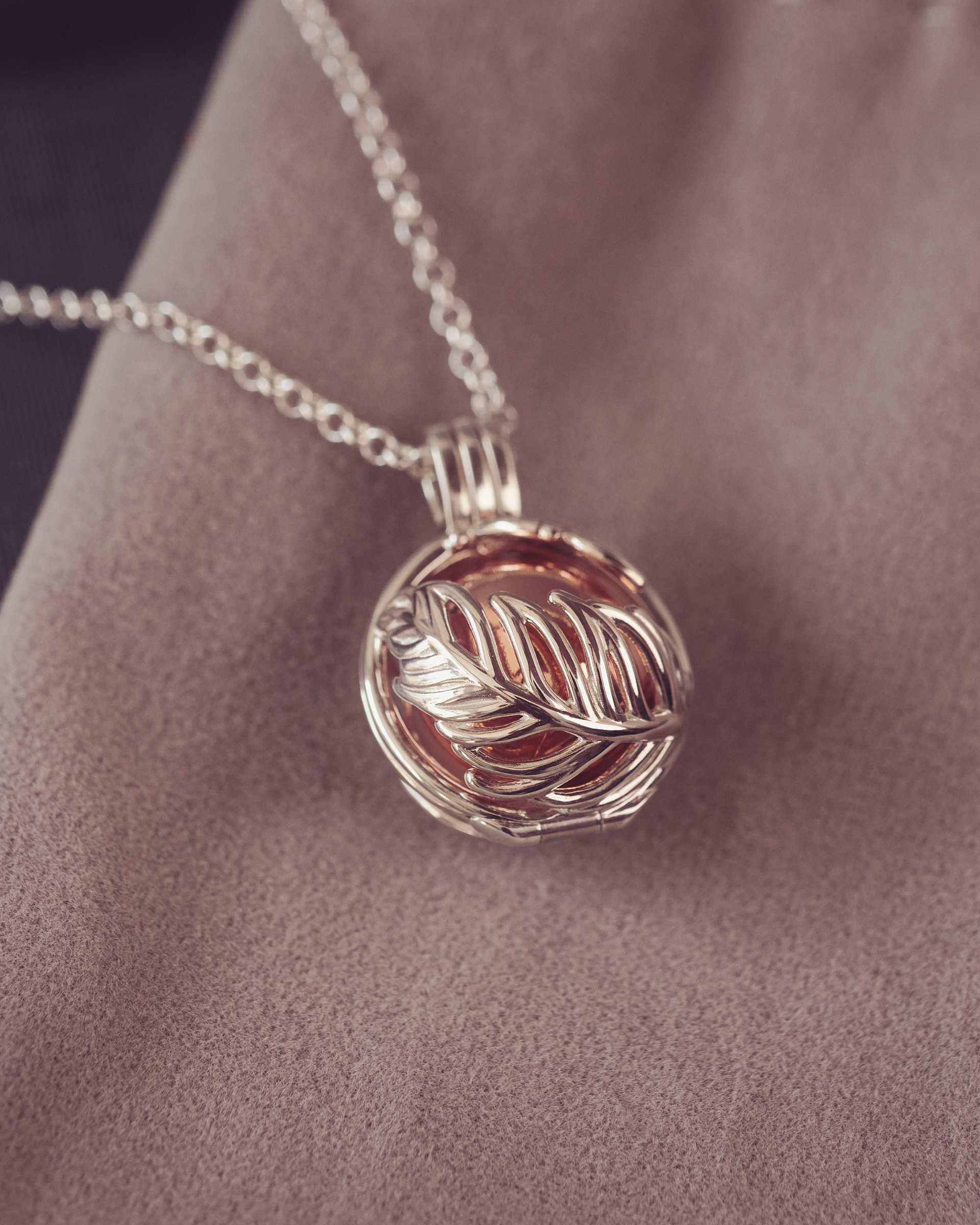 Silver necklace with a leaf-shaped pendant on fabric