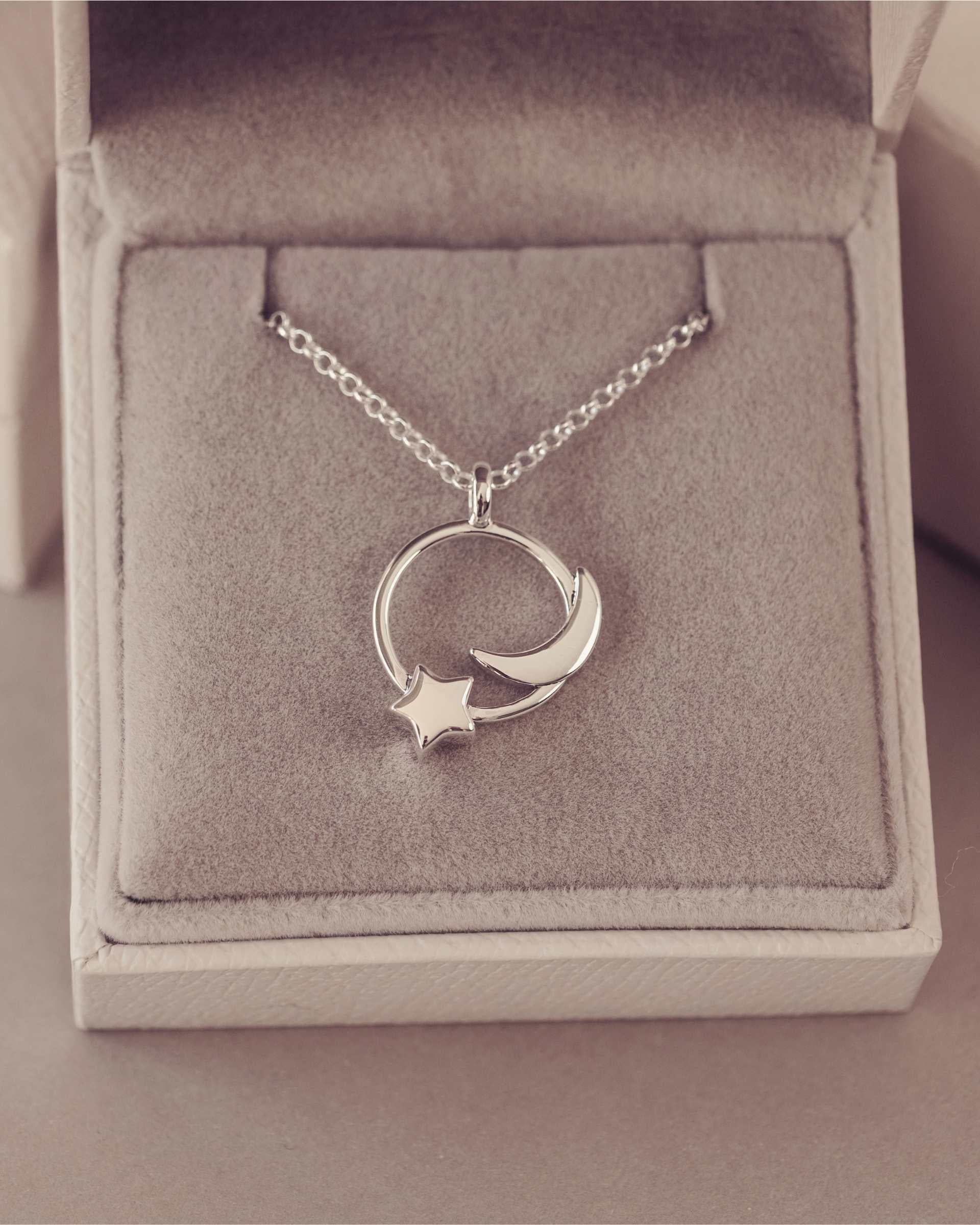 Silver necklace with a moon and star pendant in an open jewelry box.