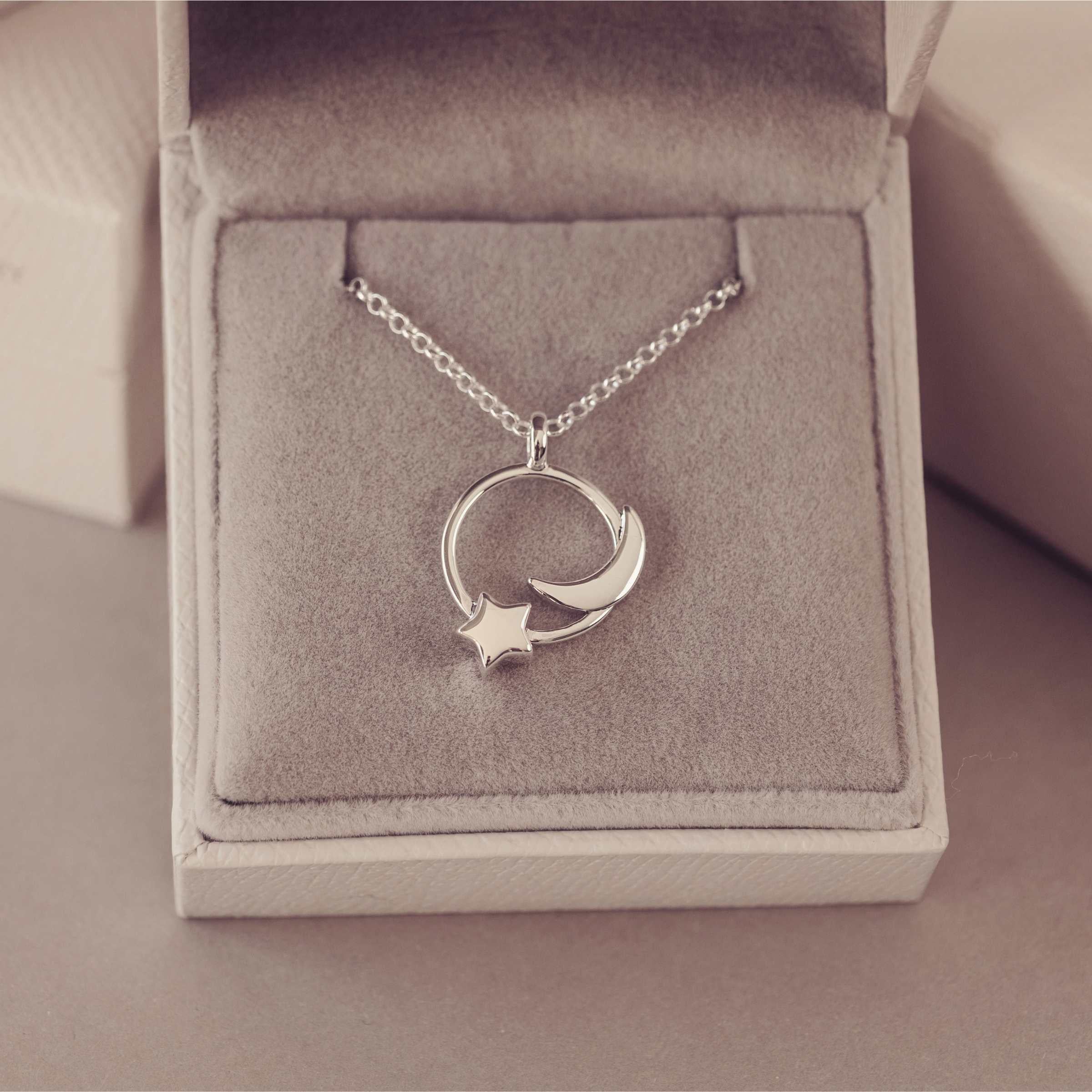 Silver necklace with a moon and star pendant in an open jewelry box.