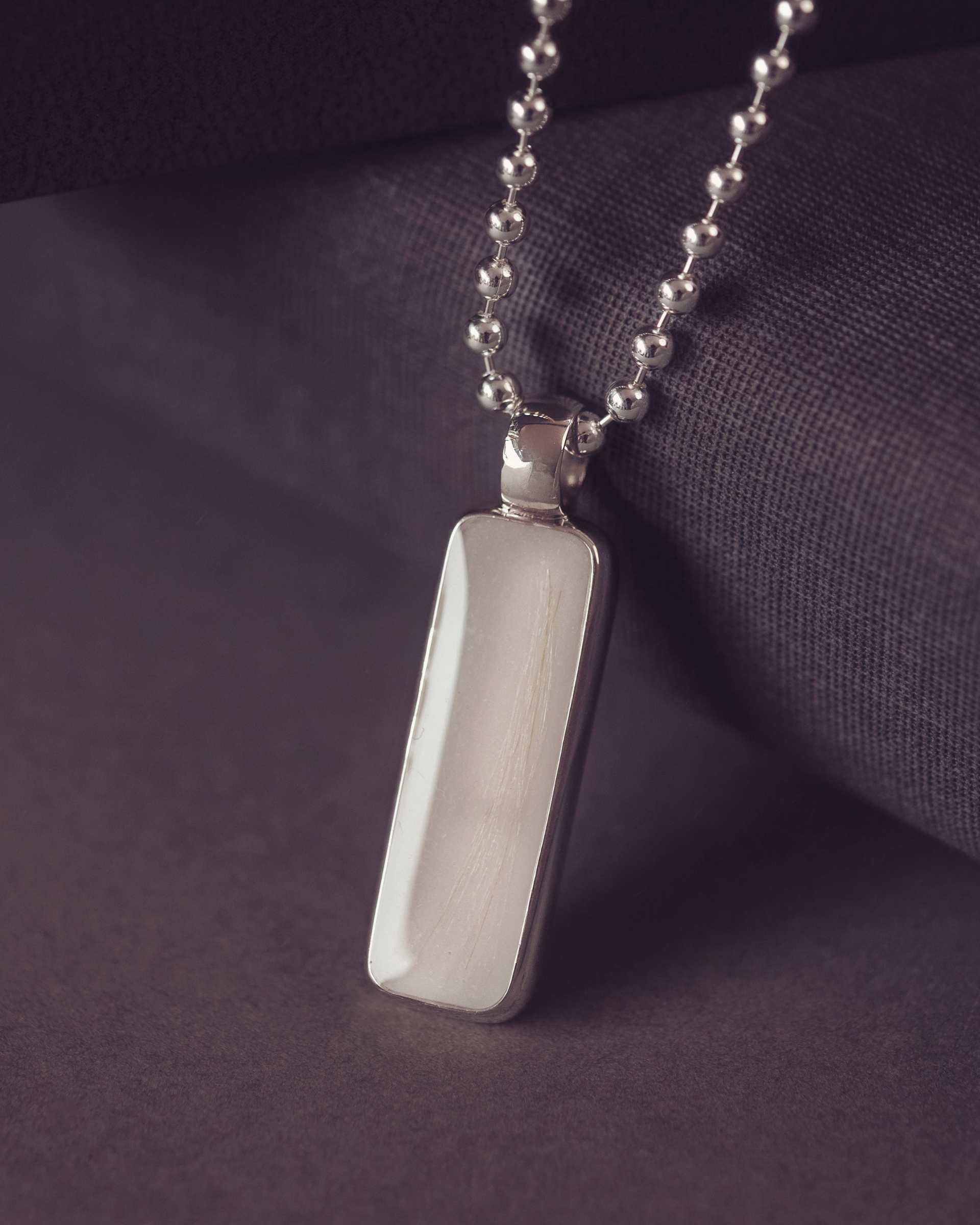 Silver pendant necklace on a dark purple fabric background