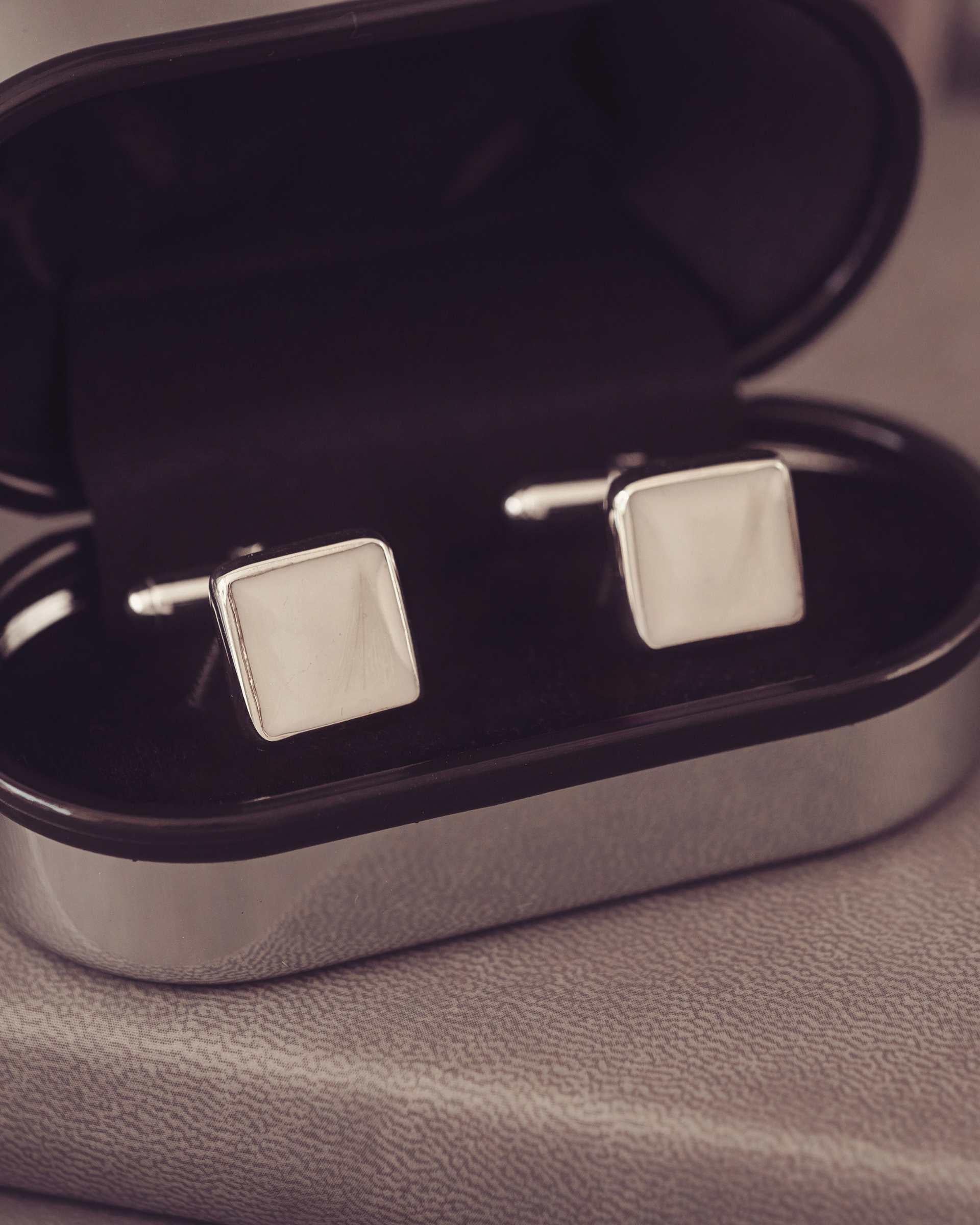 Silver square cufflinks in a silver coloured box.