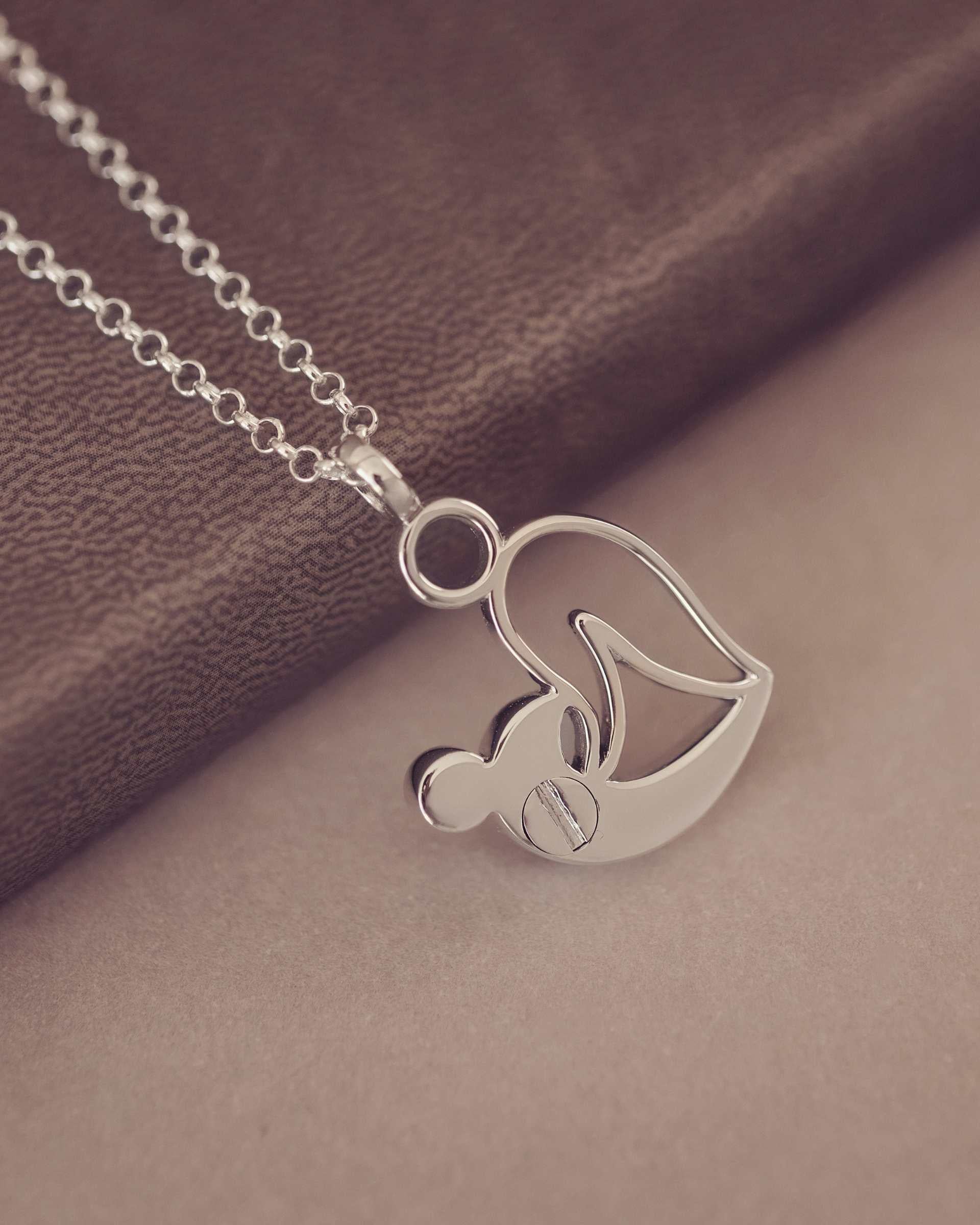 Showing the back of a Silver Urn necklace on a brown fabric background