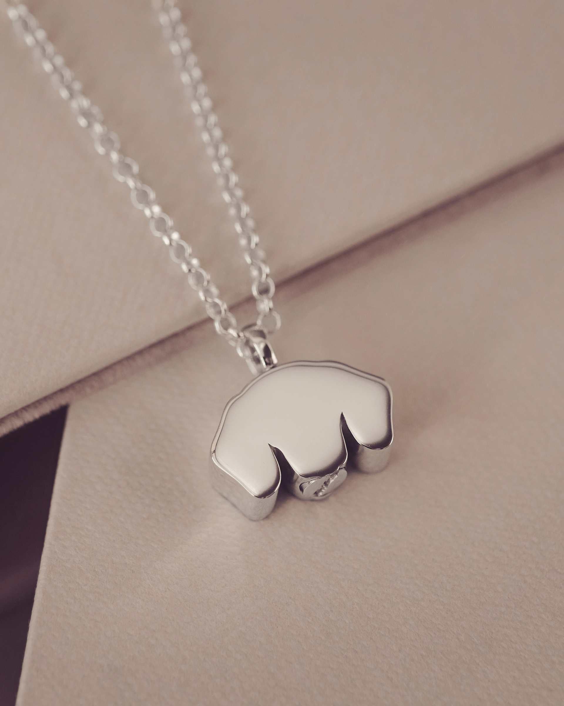 Silver necklace with a back of dog-shaped pendant on a beige surface