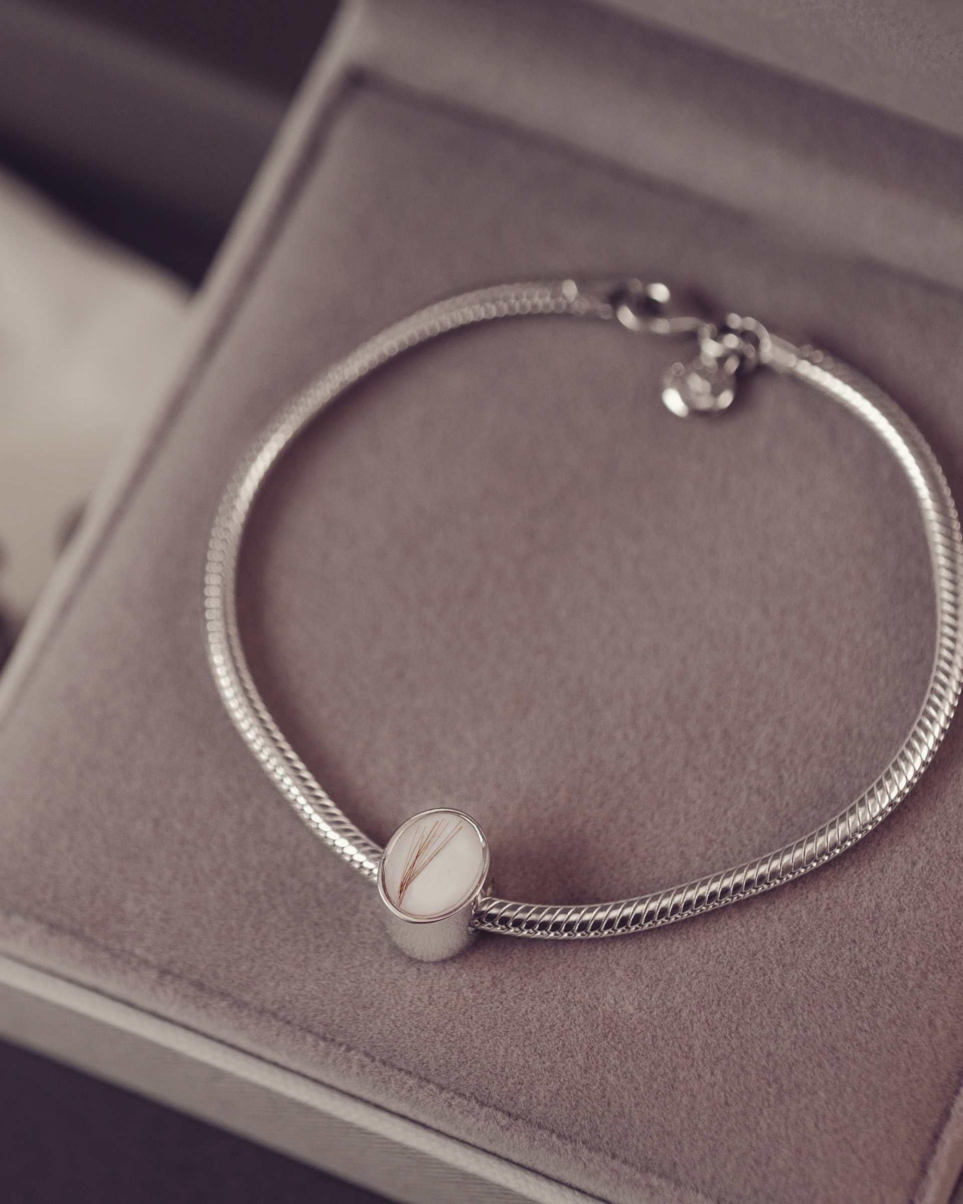 Silver bracelet with a oval charm on a soft surface