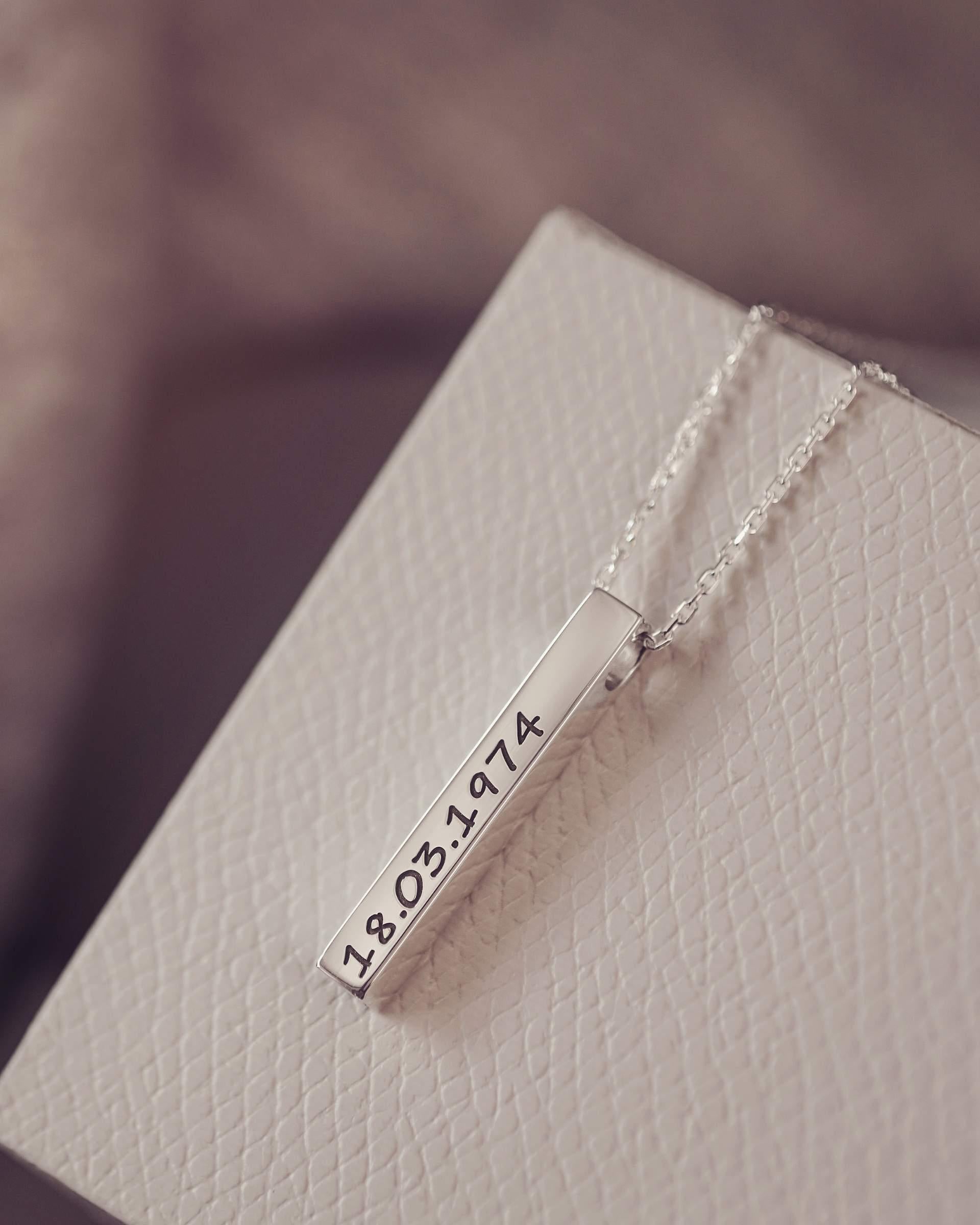Silver necklace with a bar pendant on a textured surface