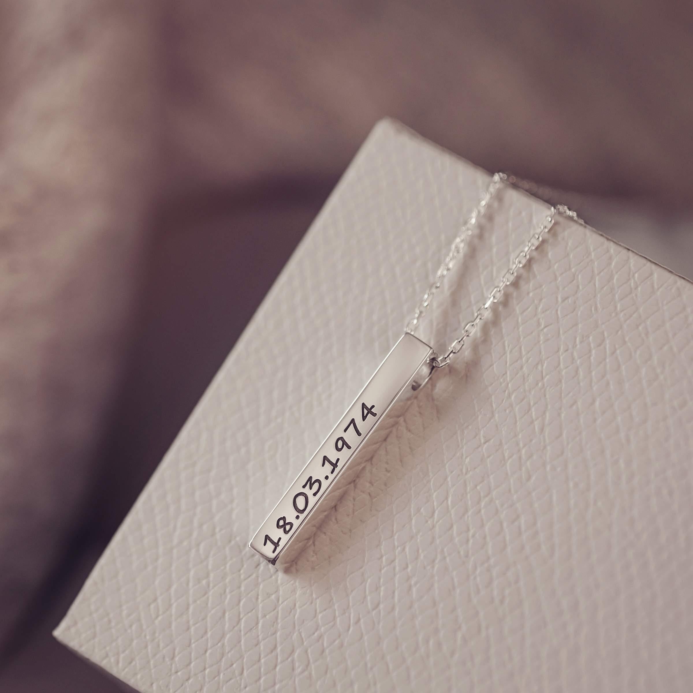 Silver necklace with a bar pendant on a textured surface
