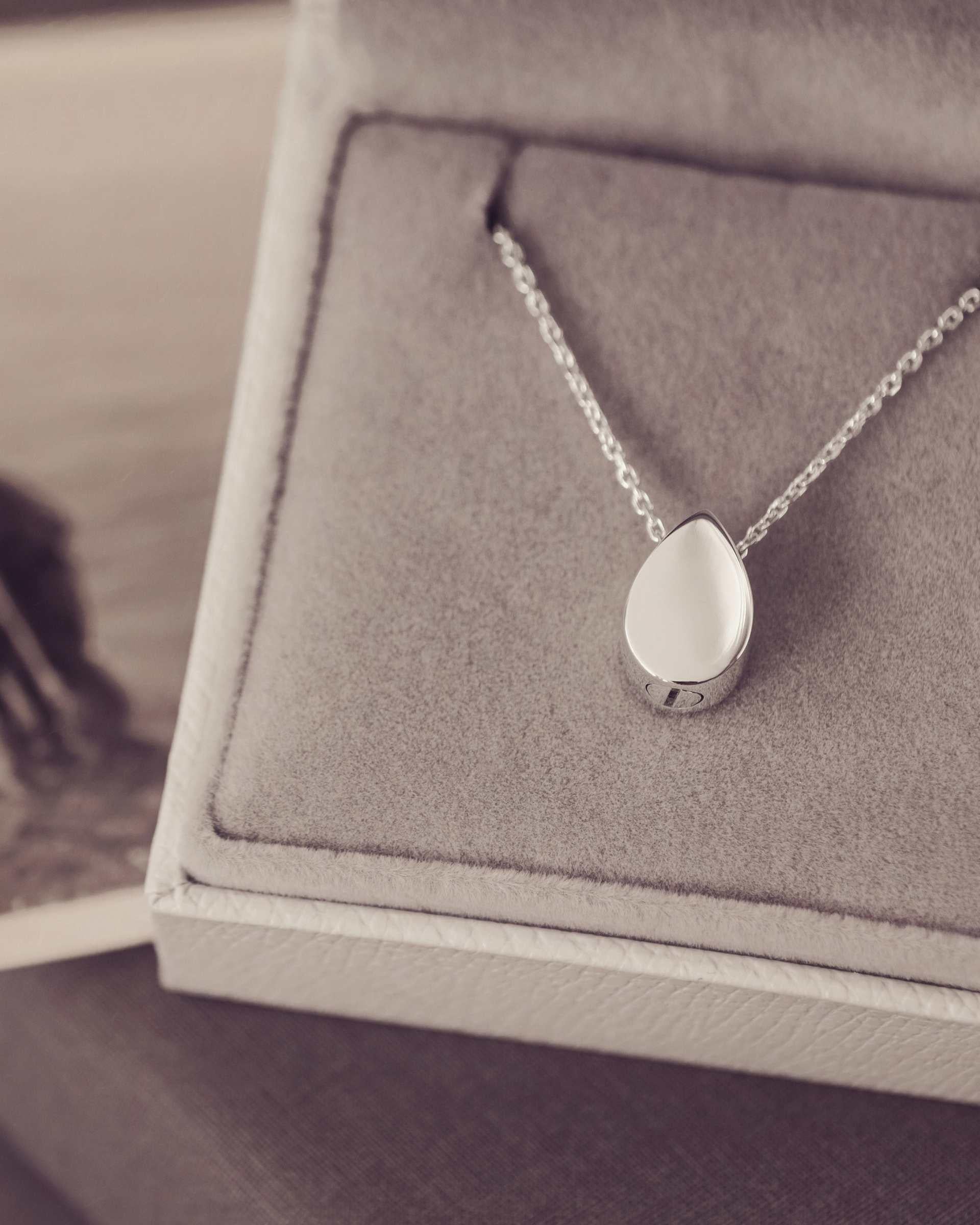 Silver Teardrop Necklace in a grey Jewellery box with a black and white photograph by its side