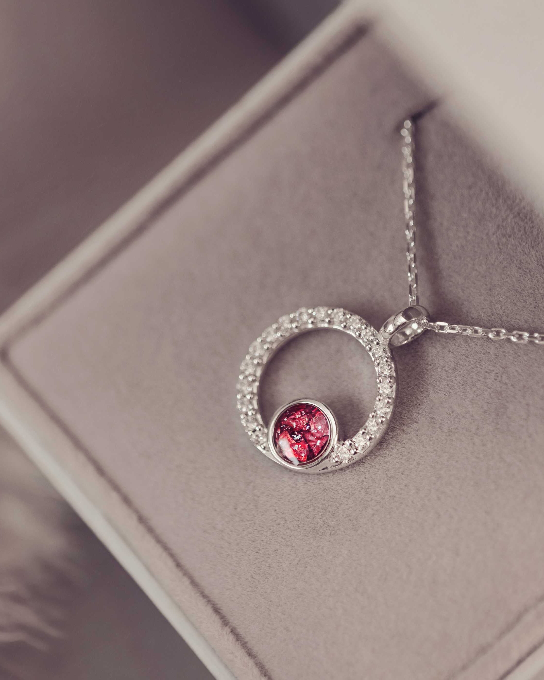 Silver necklace with a red gemstone pendant on a soft gray surface