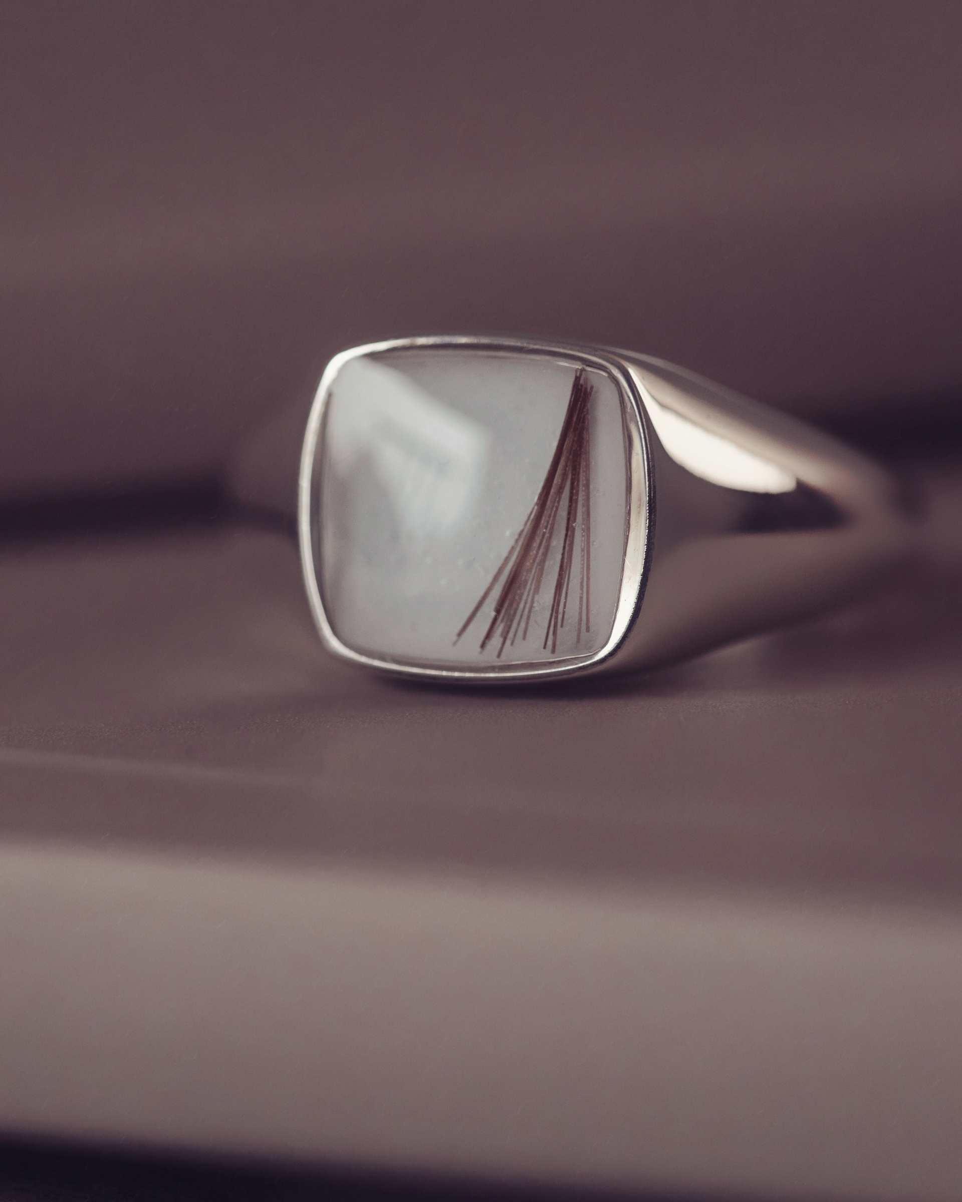 silver cushion signet ring on a dark backgrounf