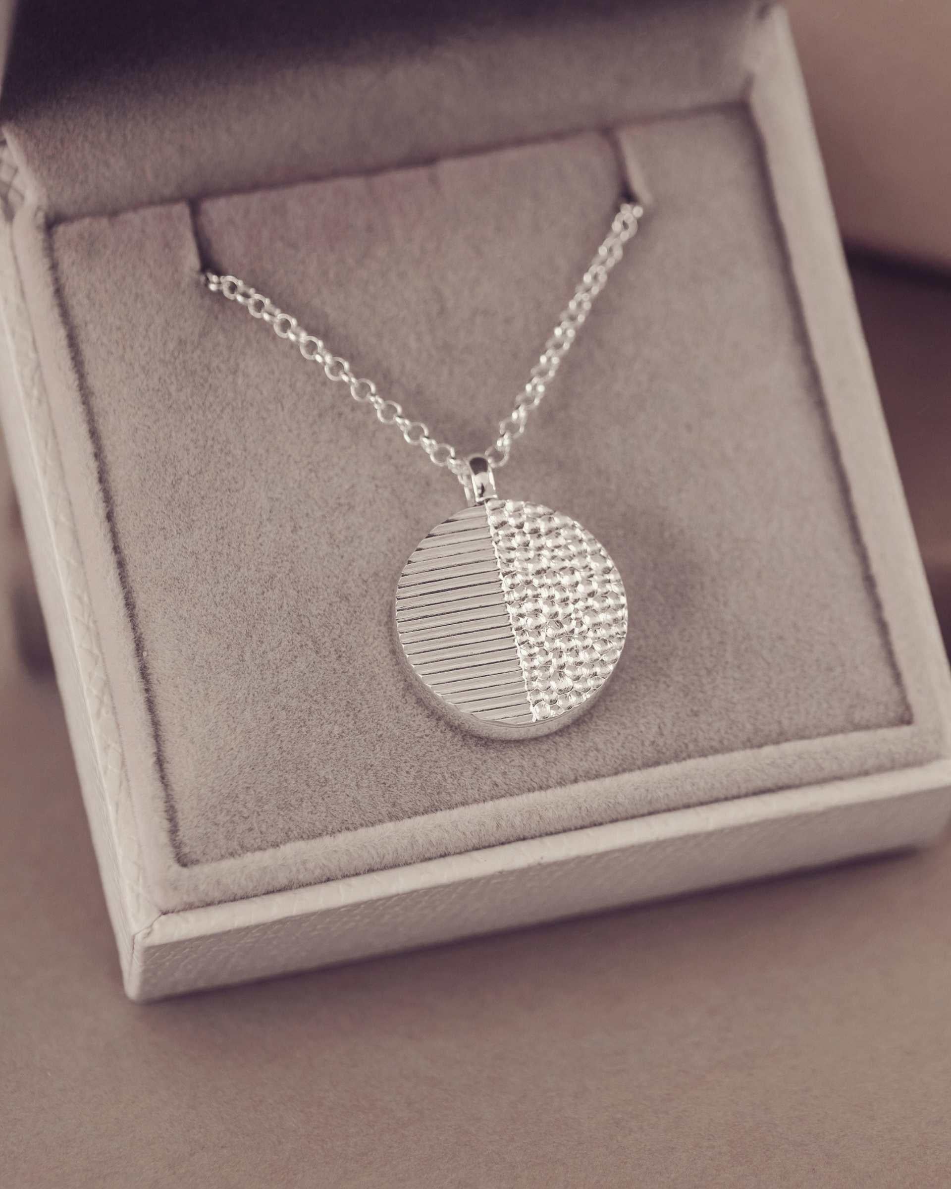Silver necklace with a round pendant in a jewellery box