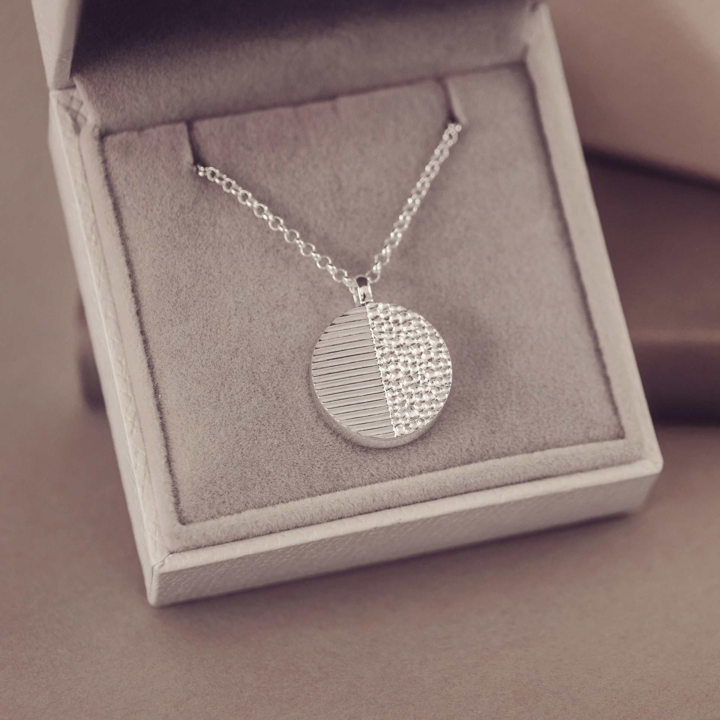 Silver necklace with a round pendant in a jewellery box