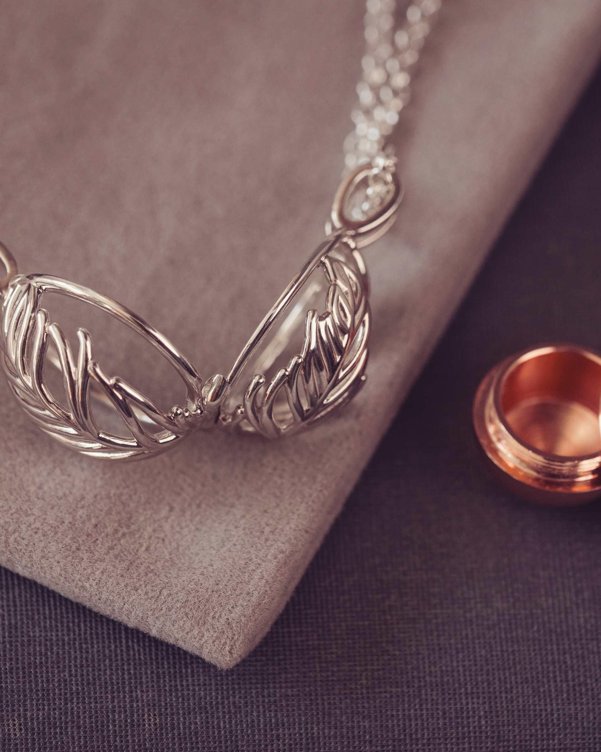 Silver necklace with feather-like pendants on a textured surface