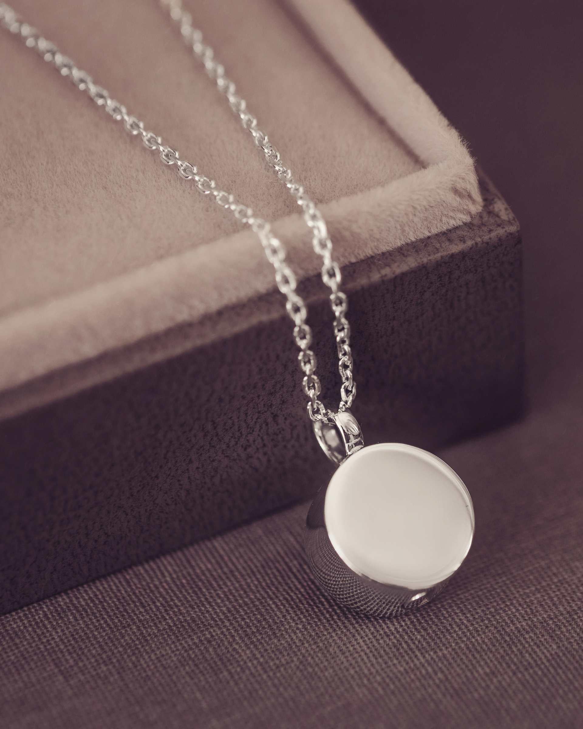 Silver necklace with a round pendant on a textured surface