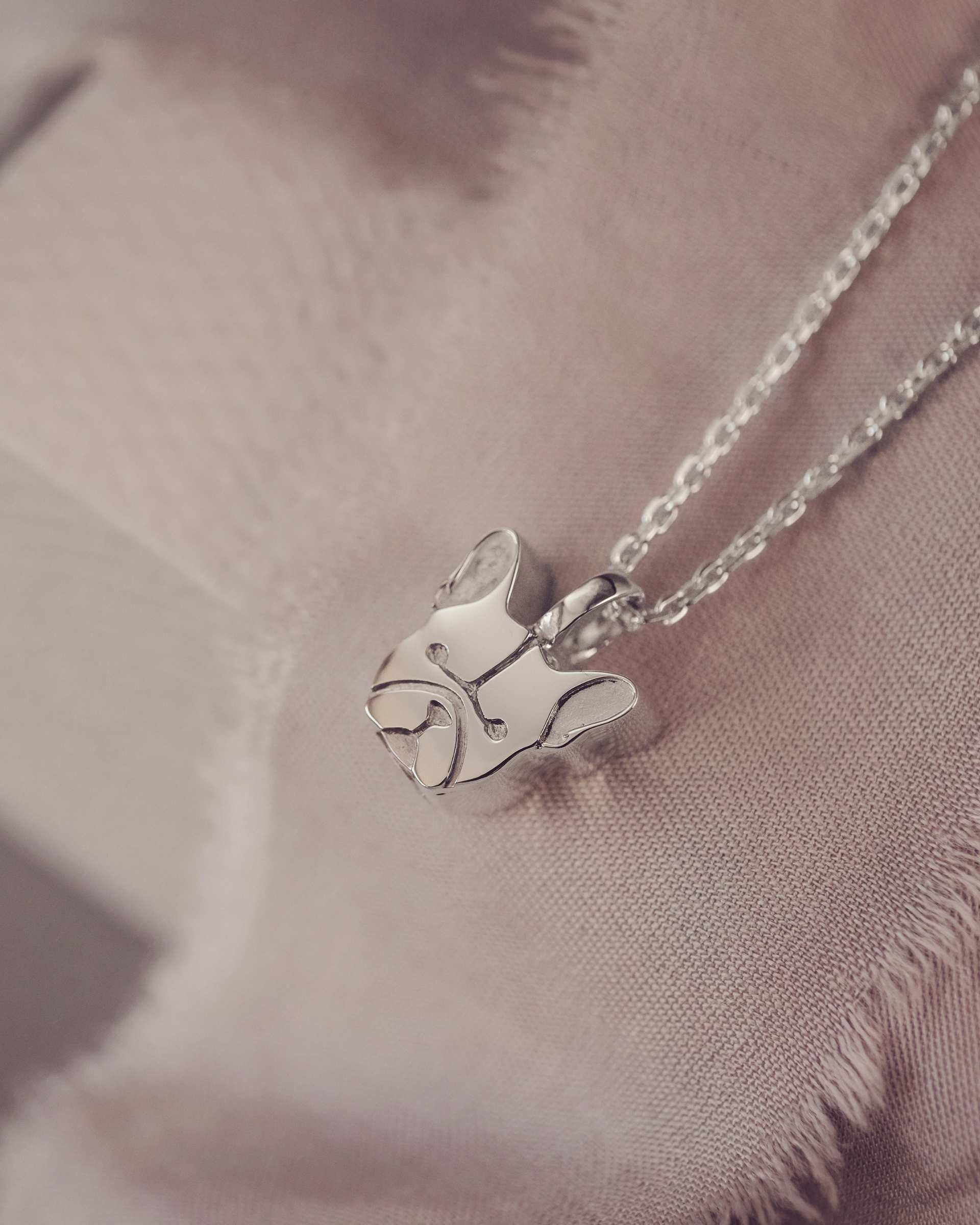 Silver French bull dog pendant necklace on a soft fabric background
