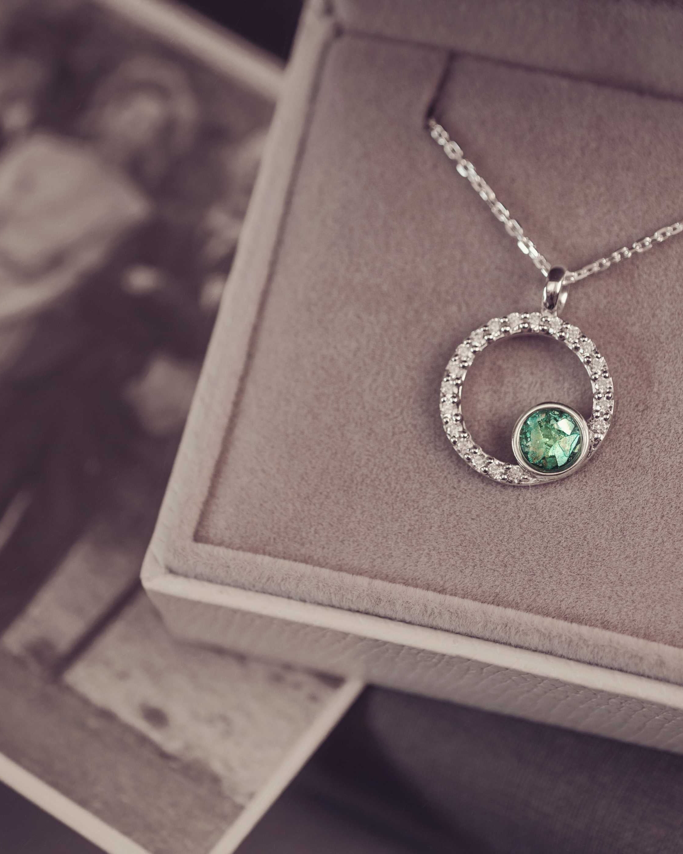 Silver necklace with a green gemstone pendant on a textured surface