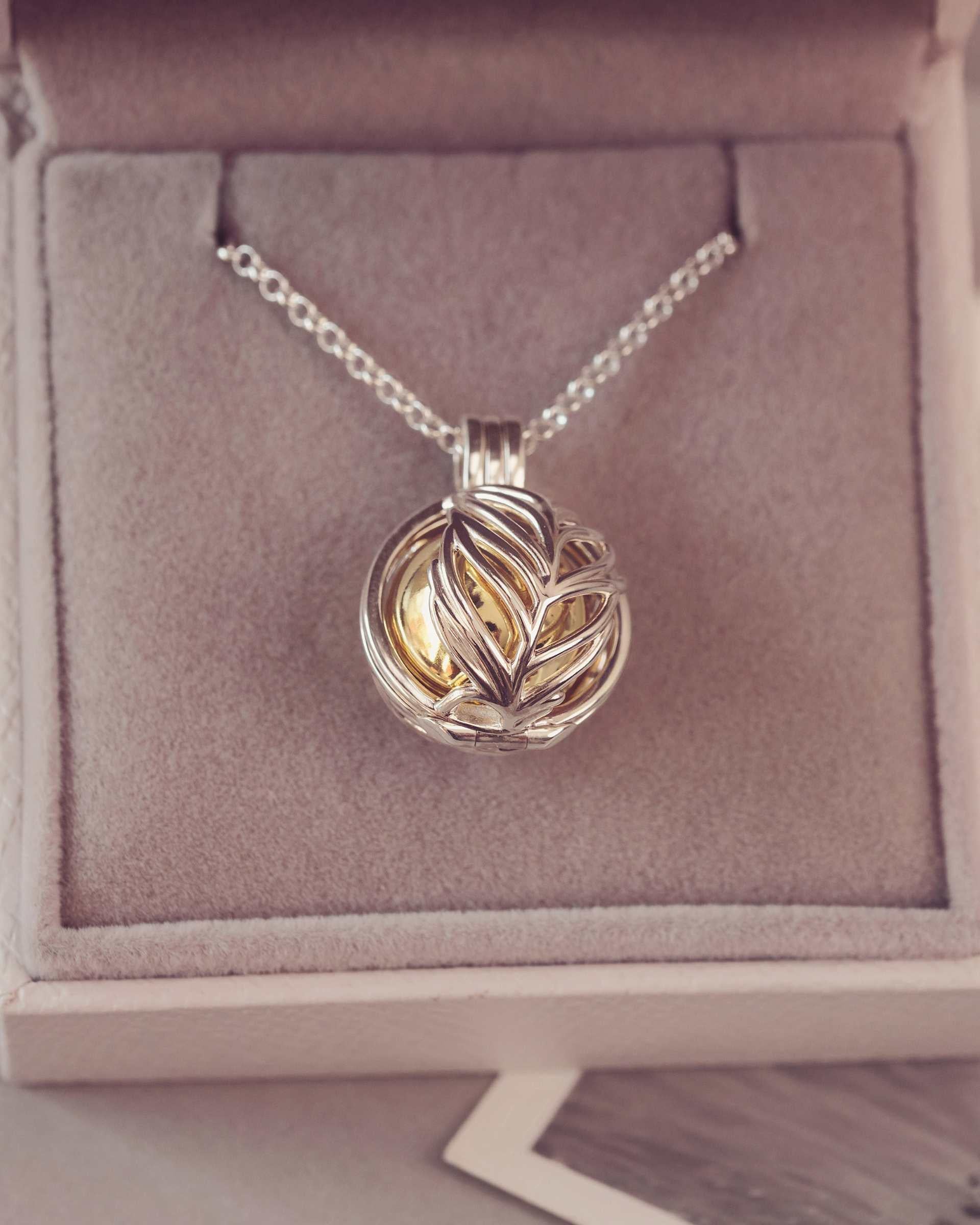 Silver and gold feather necklace pendant in a jewelry box.