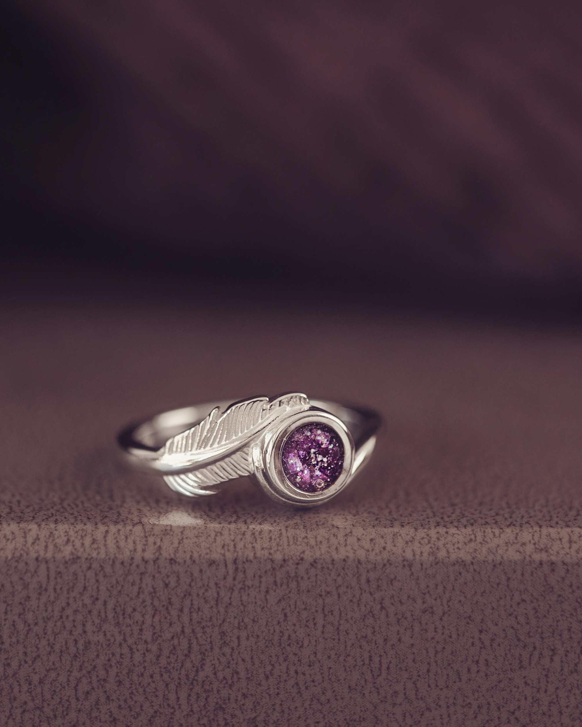 A silver purple ash filled feather ring in a jewellery box