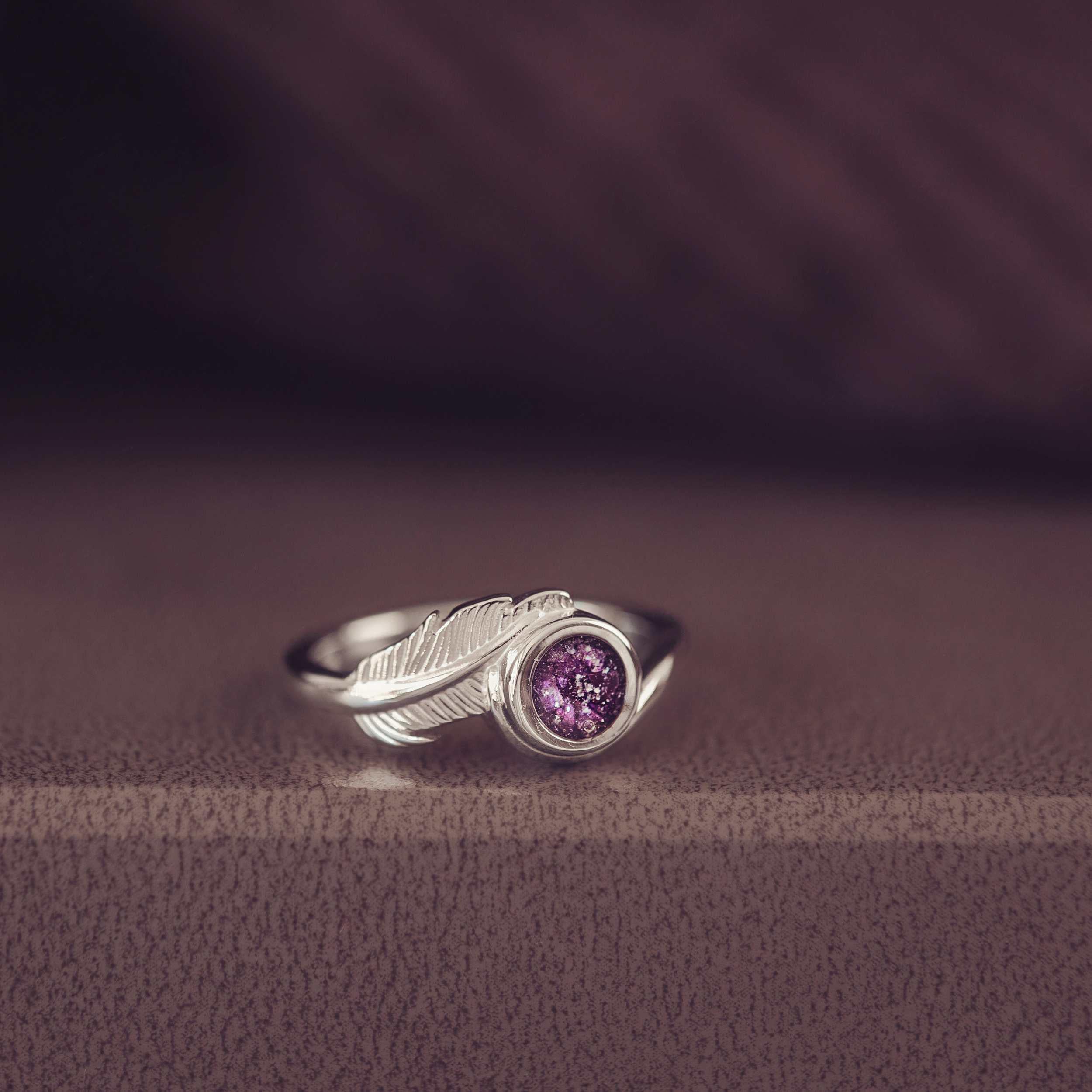 A silver purple ash filled feather ring in a jewellery box