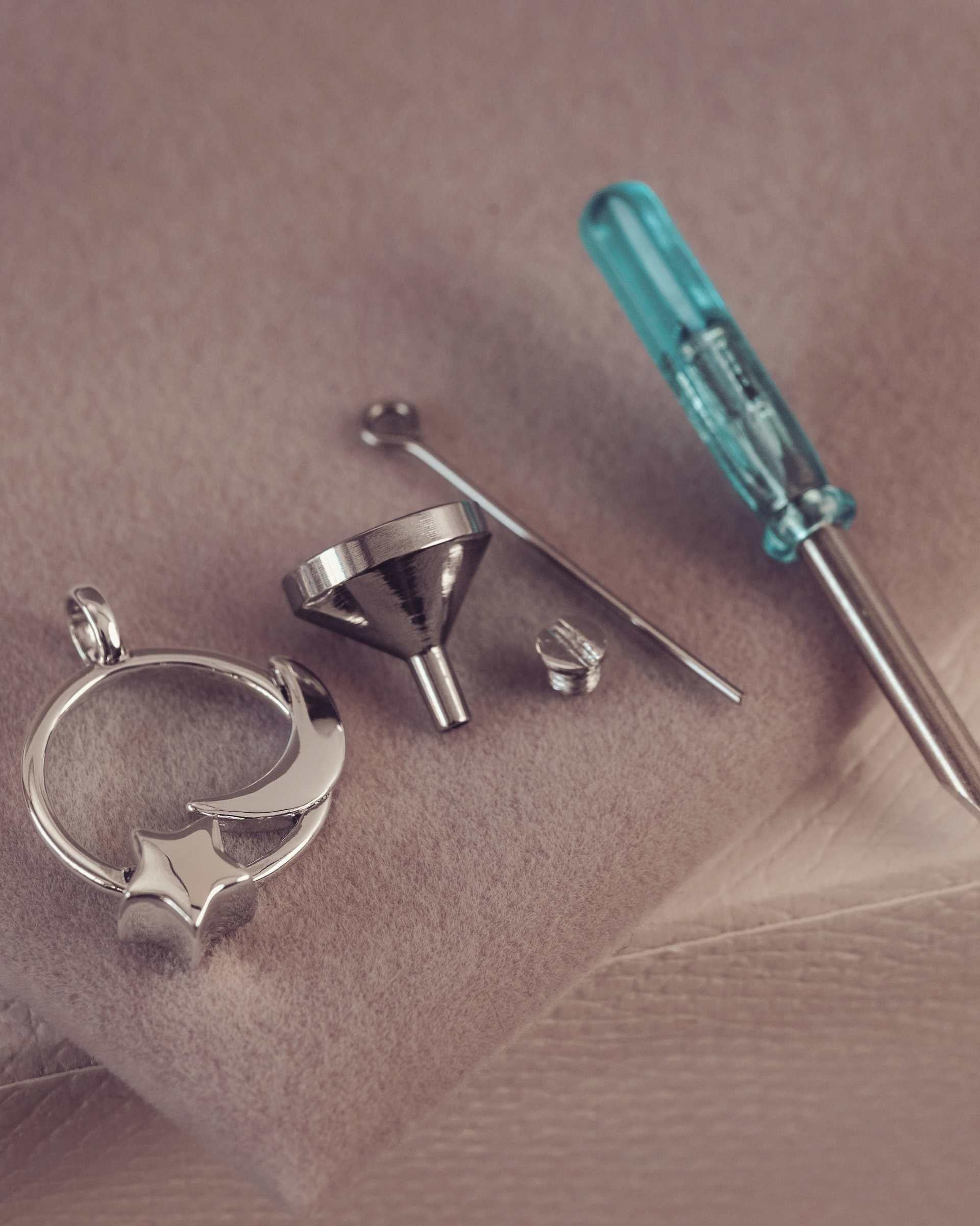 Metal jewelry components and a screwdriver on a textured surface