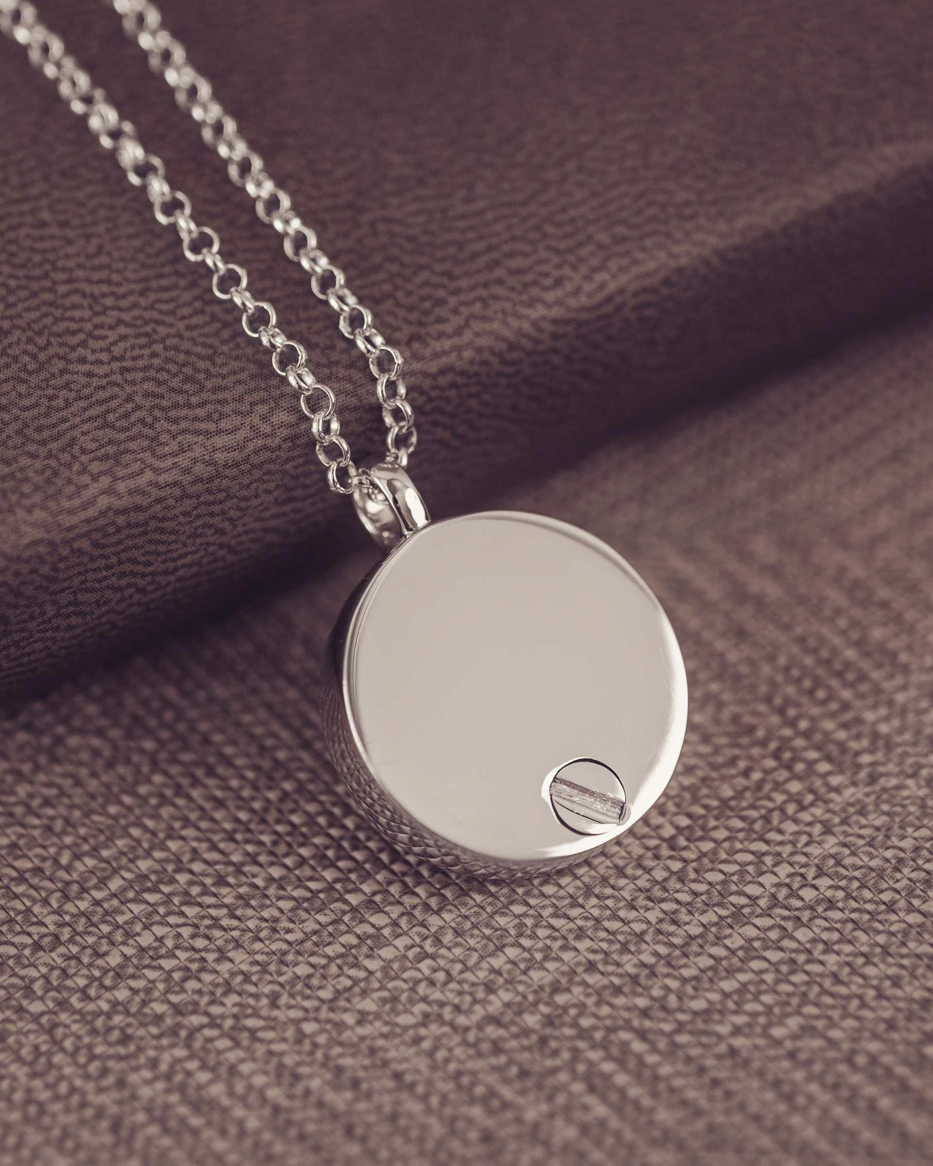Silver pendant necklace on a textured brown fabric background