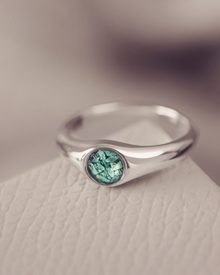 Silver ring with a green gemstone on a textured surface