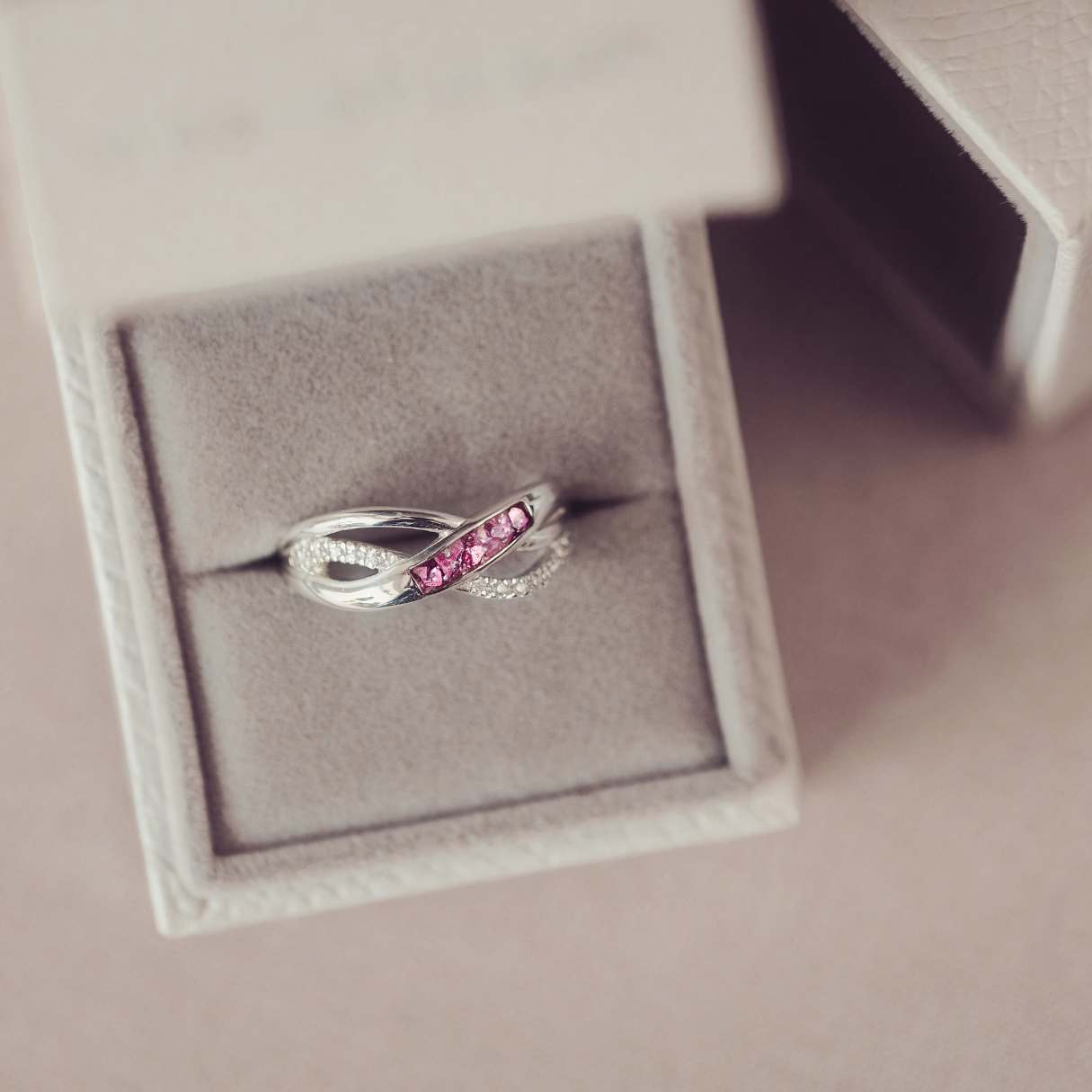Silver ring with pink gemstones in a jewelry box