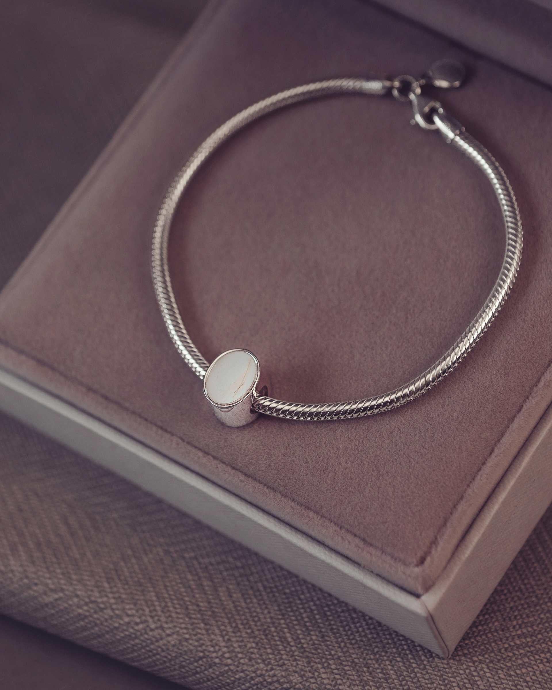 Silver bracelet with an oval charm on a jewellery box