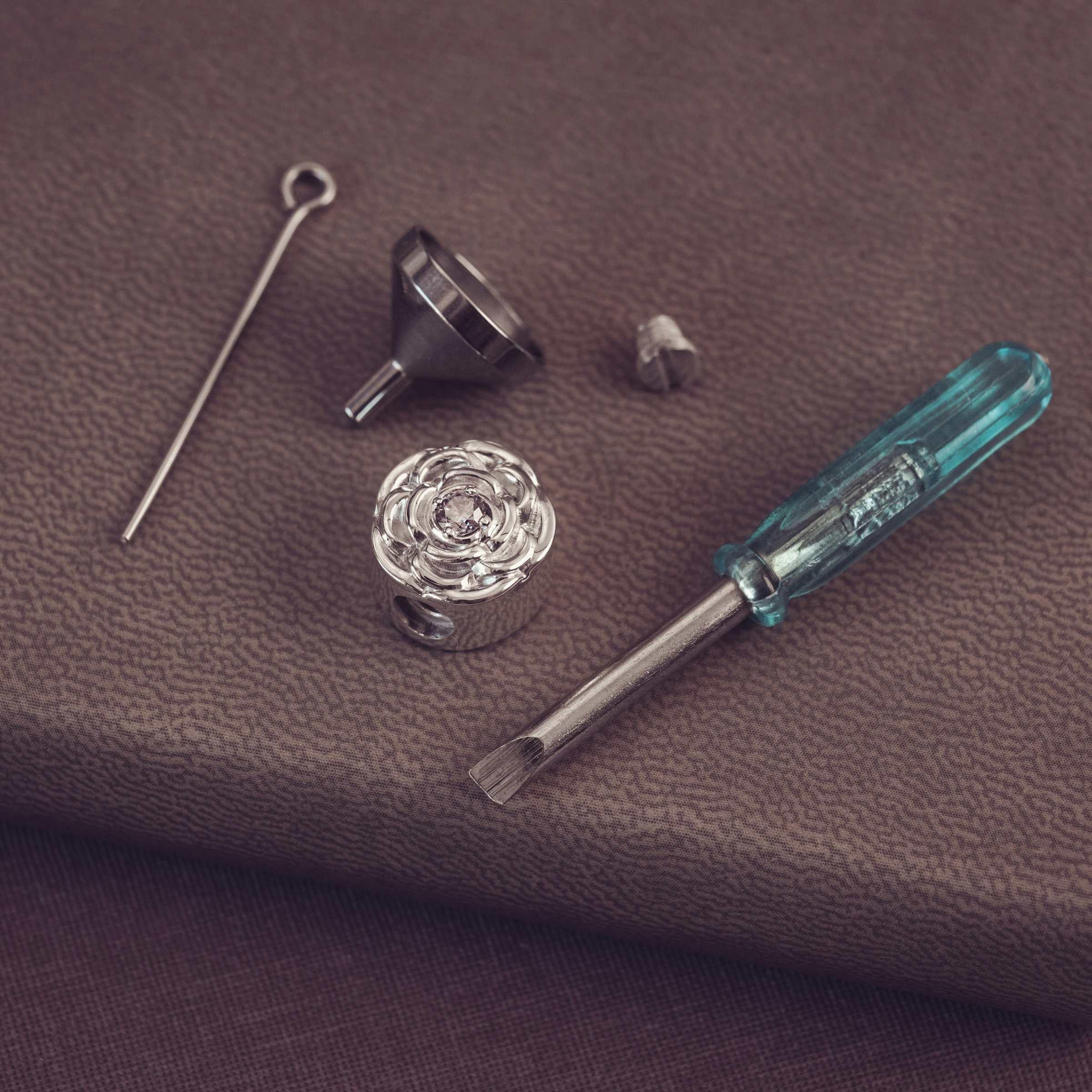 Set of small tools including a screwdriver, funnel, and metal rod on a brown surface